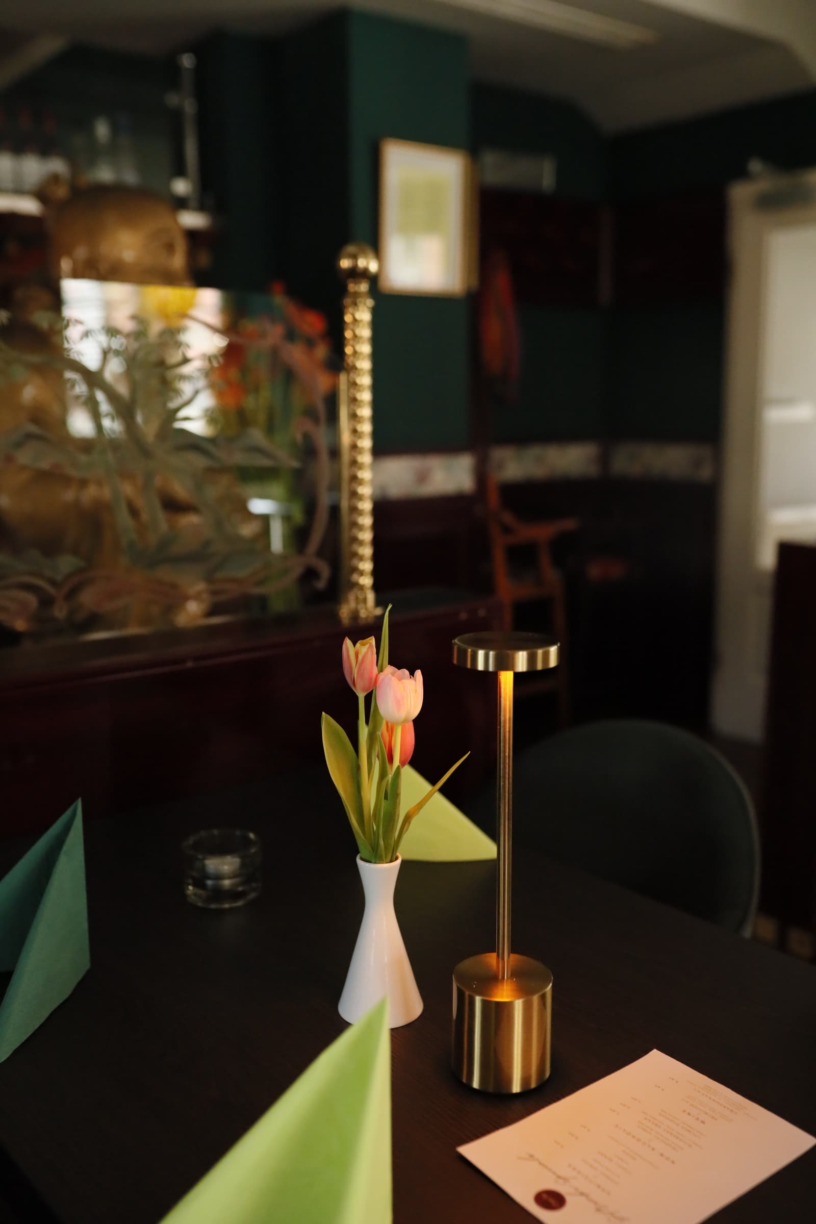 Restaurant-Tisch, stilvoll gedeckt mit Blumen, Kerze und Speisekarte. Gemütliche Atmosphäre.