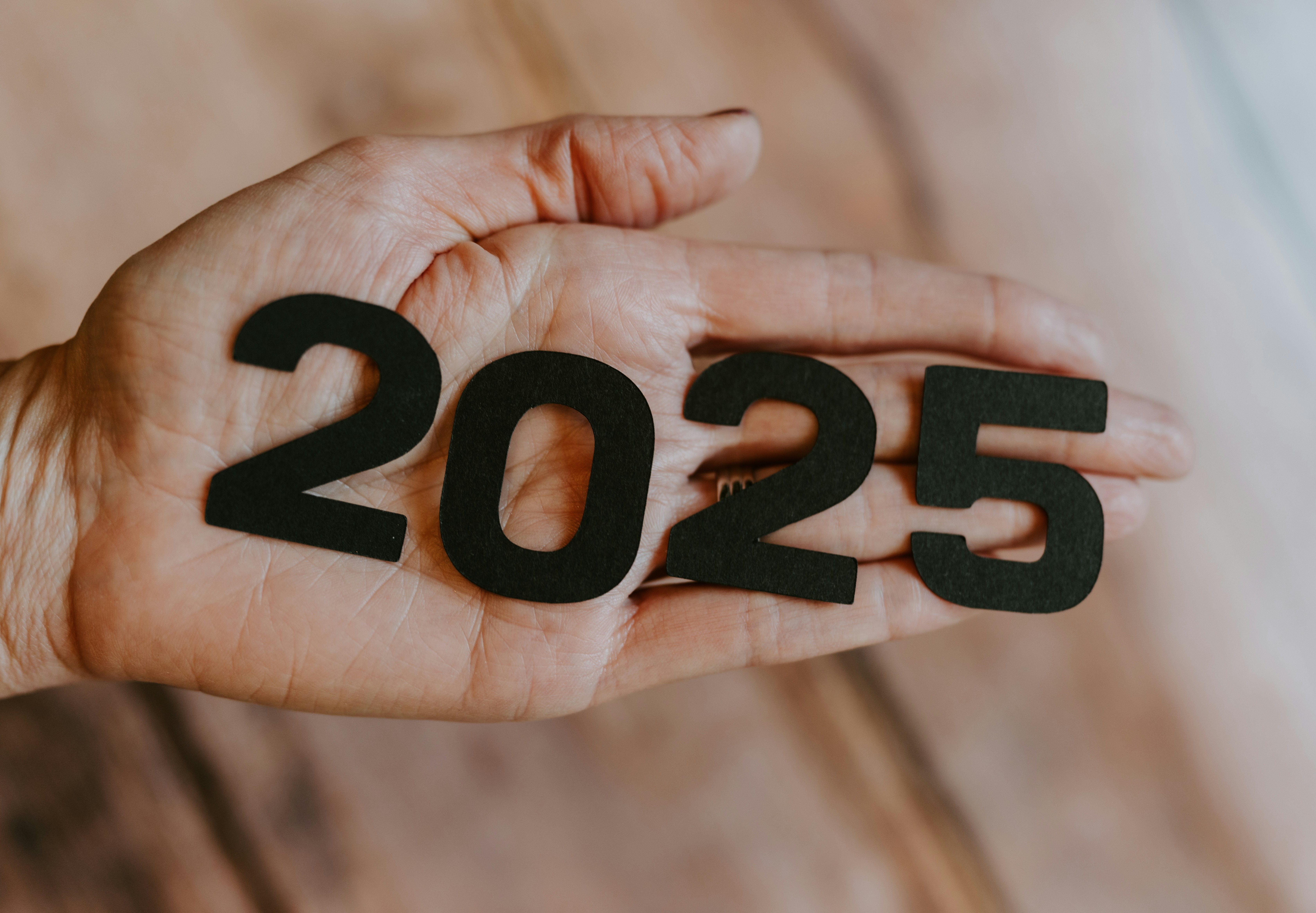 Close-up of a hand holding black cutout numbers forming '2025', symbolizing the new year or a future-focused blog topic.