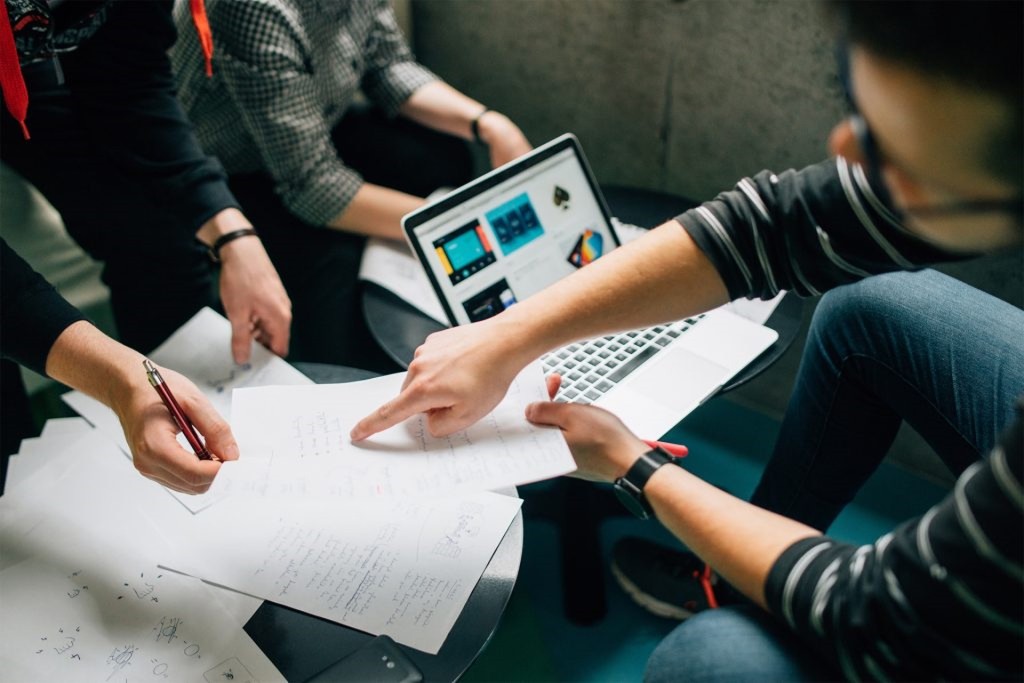 A photo of a group of people lookig at data and using a computer