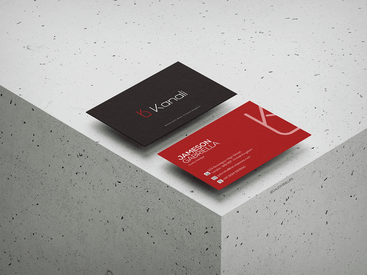 Two business cards in black and red, resting on a white surface with a subtle shadow.