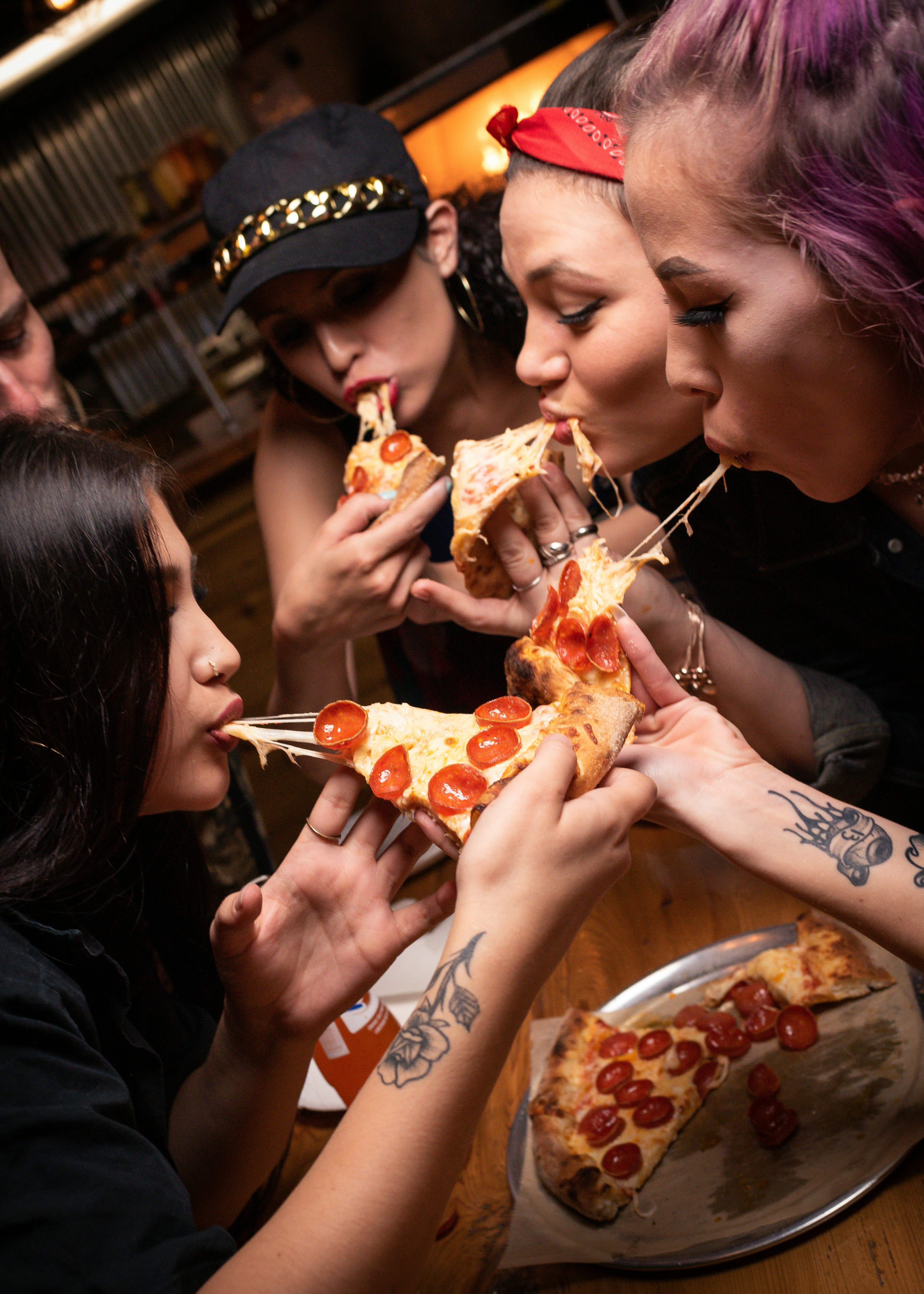 Group of friends sharing cheesy pepperoni pizza slices