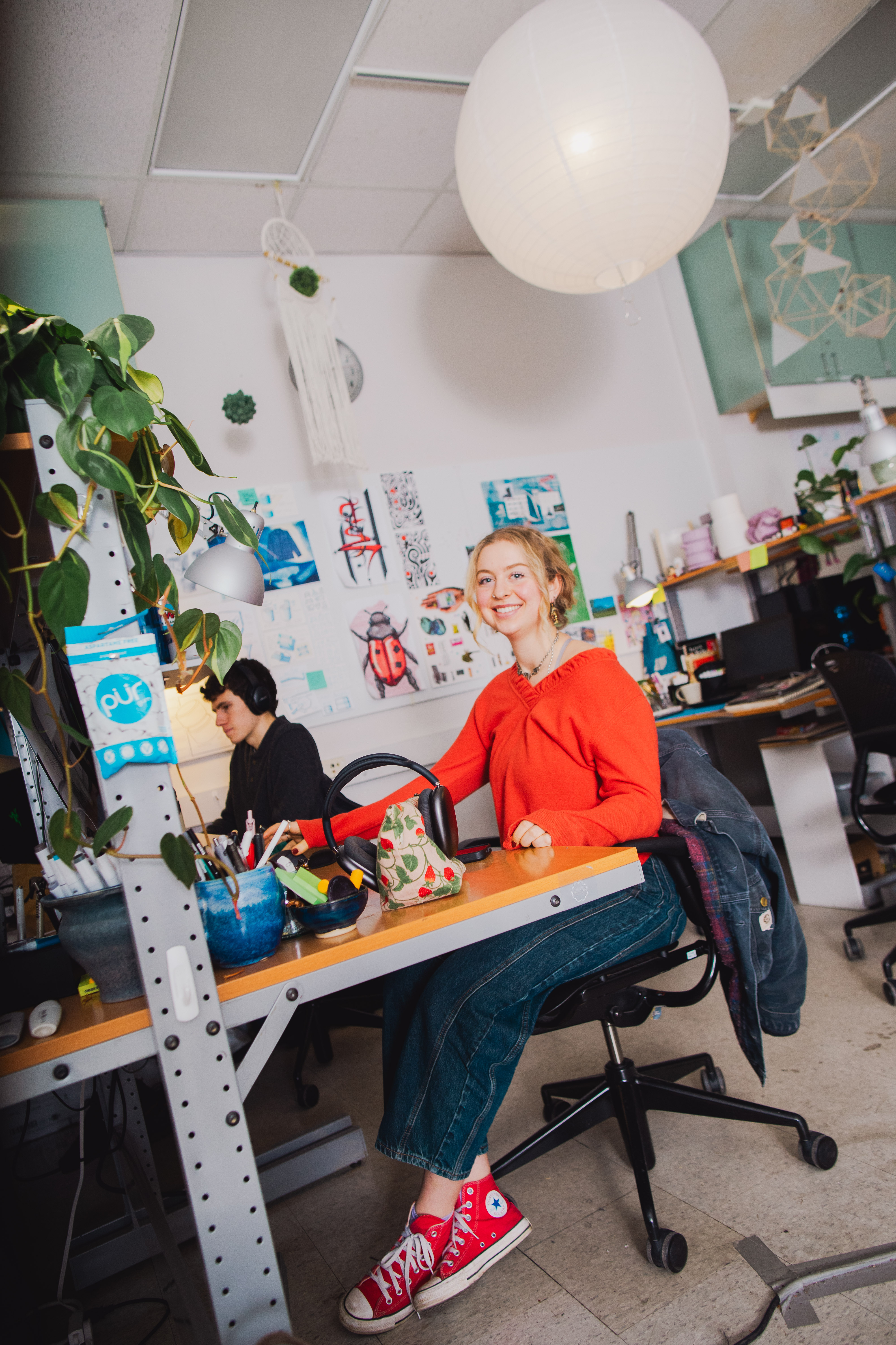 A person in a winter coat and furry hat walking along a snow-covered path through a forest of frosted trees.