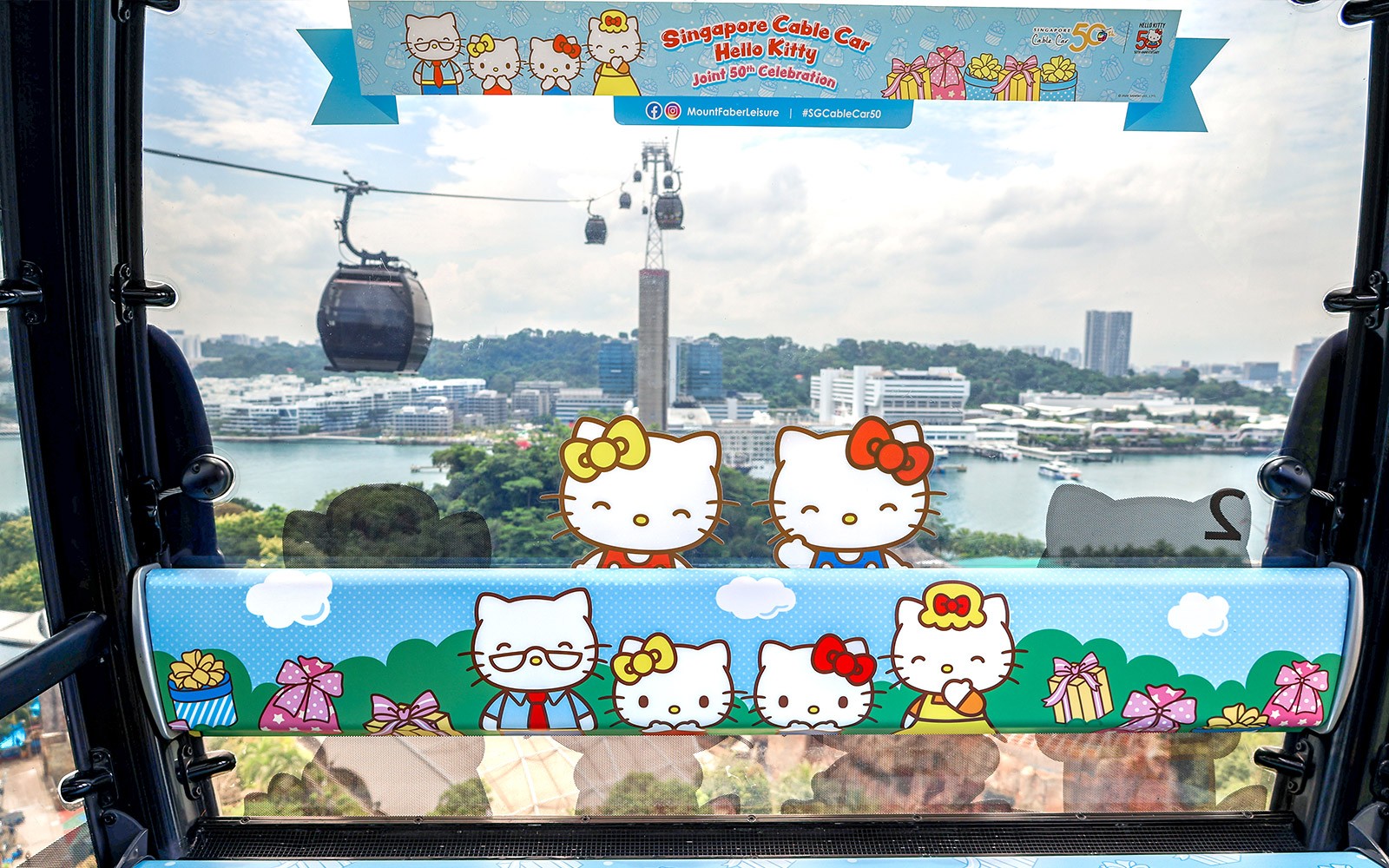 Interno della funivia a tema Hello Kitty con vista sullo skyline e sul porto di Singapore.