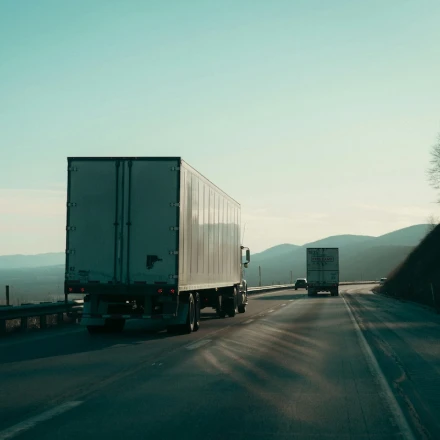 Box truck driving on a highway through the mountains, representing interstate trucking subject to FMCSA insurance requirements.