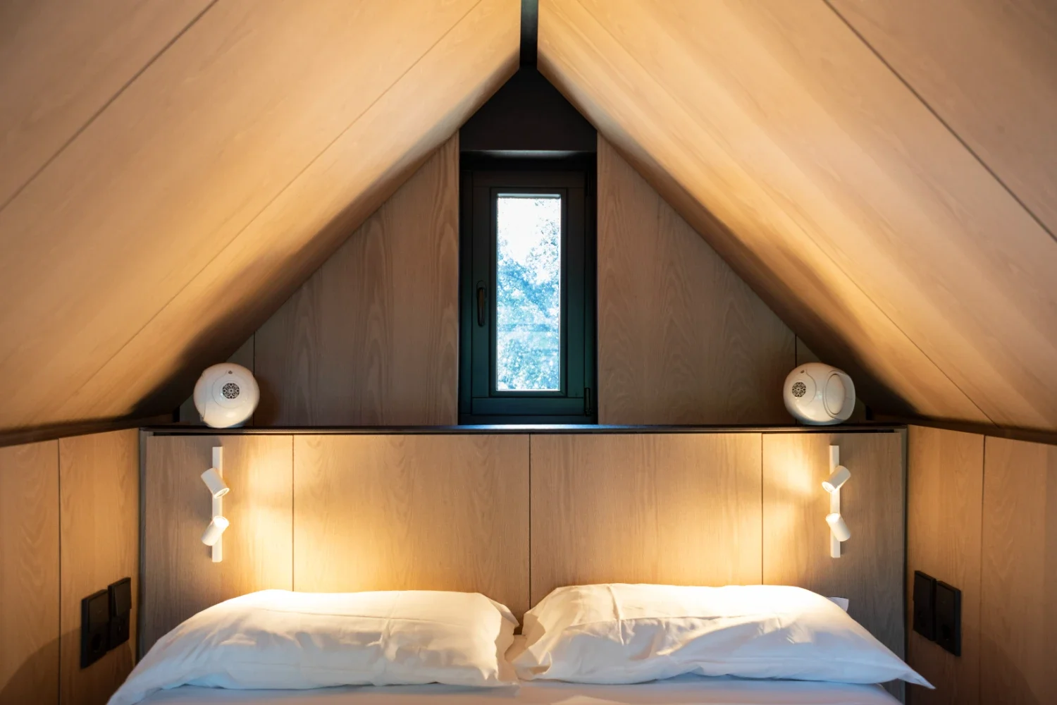 Chambre sous les toits de l'écolodge Villa Médicis, lit blanc et éclairage chaleureux