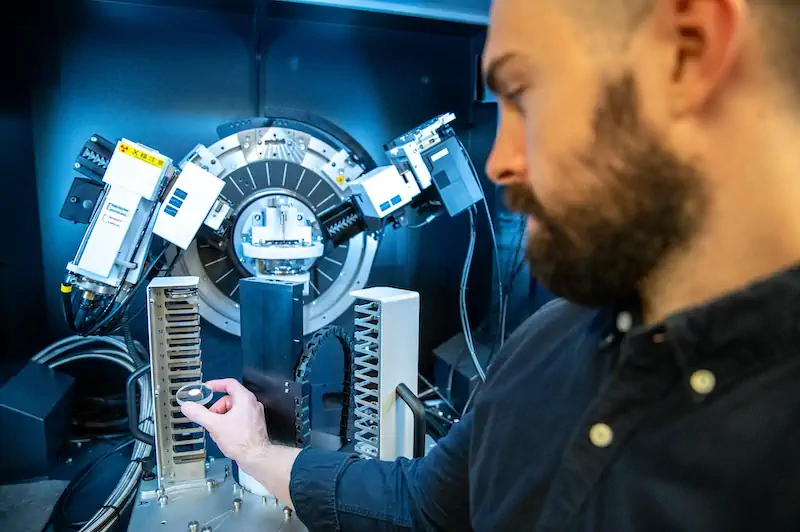 A researcher adjusting equipment inside a high-tech scientific lab with circular machinery and sensors.