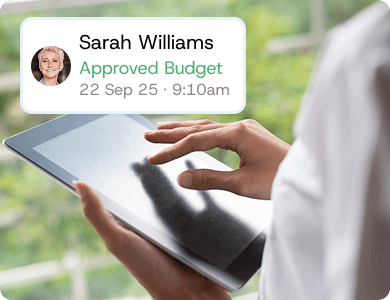 Person holding a tablet with a digital notification showing “Sarah Williams – Approved Budget,” symbolising contractor approvals and accountability.