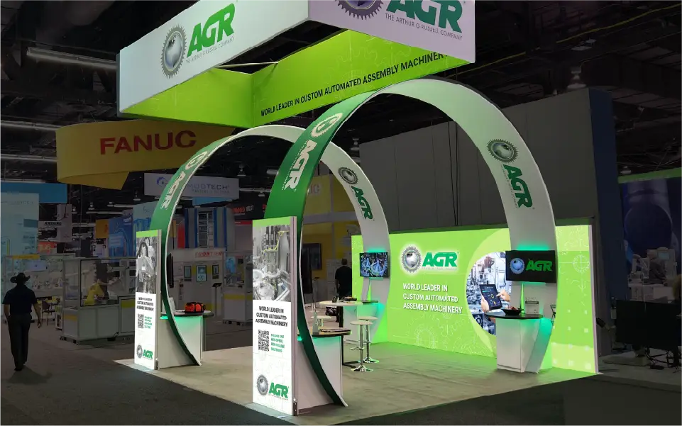 20×20 custom island booth with LED video wall and demo zones—hybrid custom exhibit fabrication example.