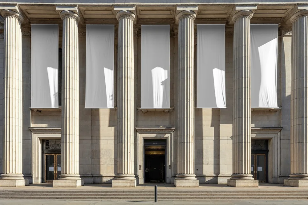 Mockup of large vertical banners hanging between grand stone columns of a neoclassical building. The vibrant red and blue banners contrast with the beige façade, creating a bold and striking visual for event or promotional displays.