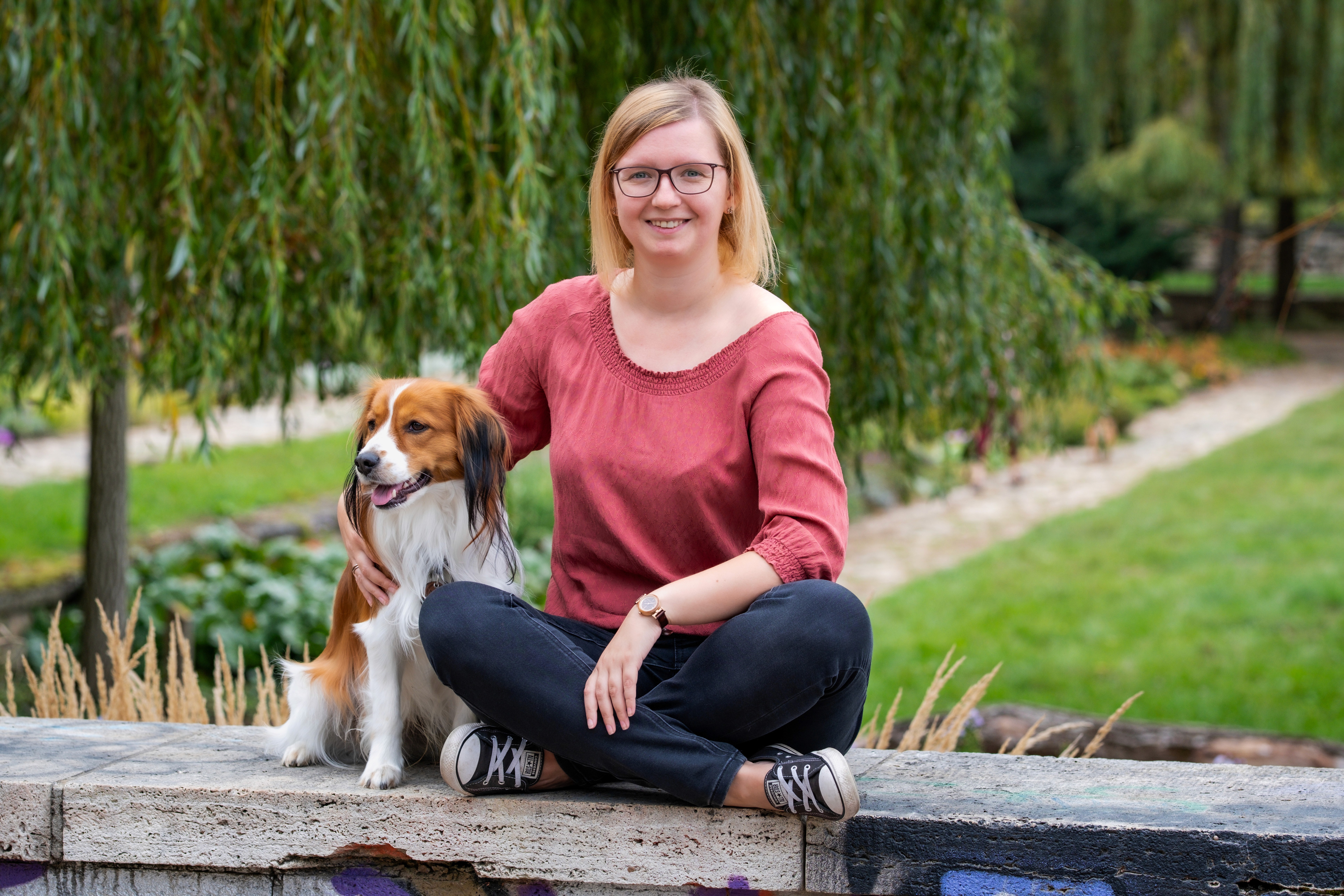 woman smiling holding short-coat brown dog
