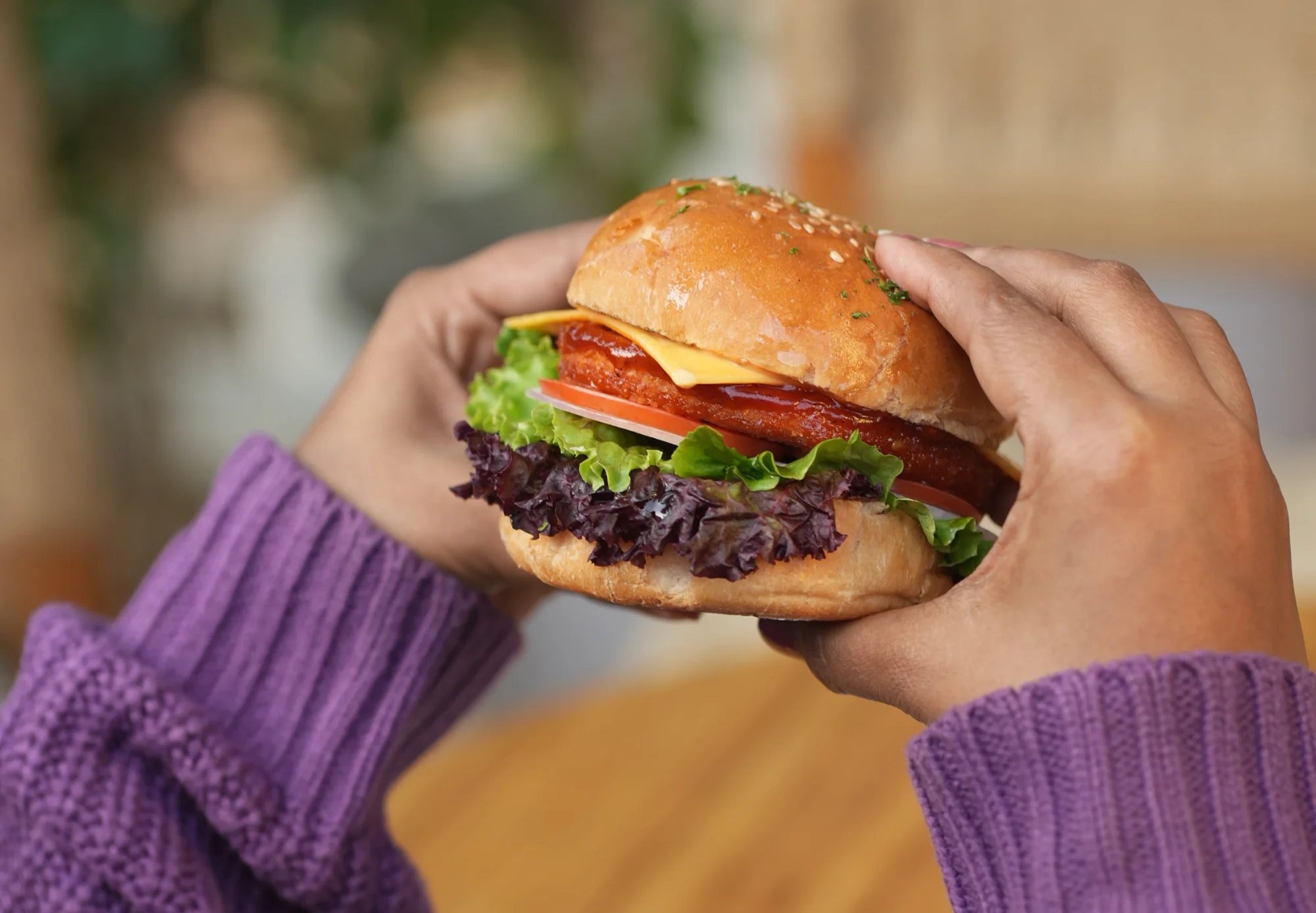 Hands holding a fully dressed hamburger