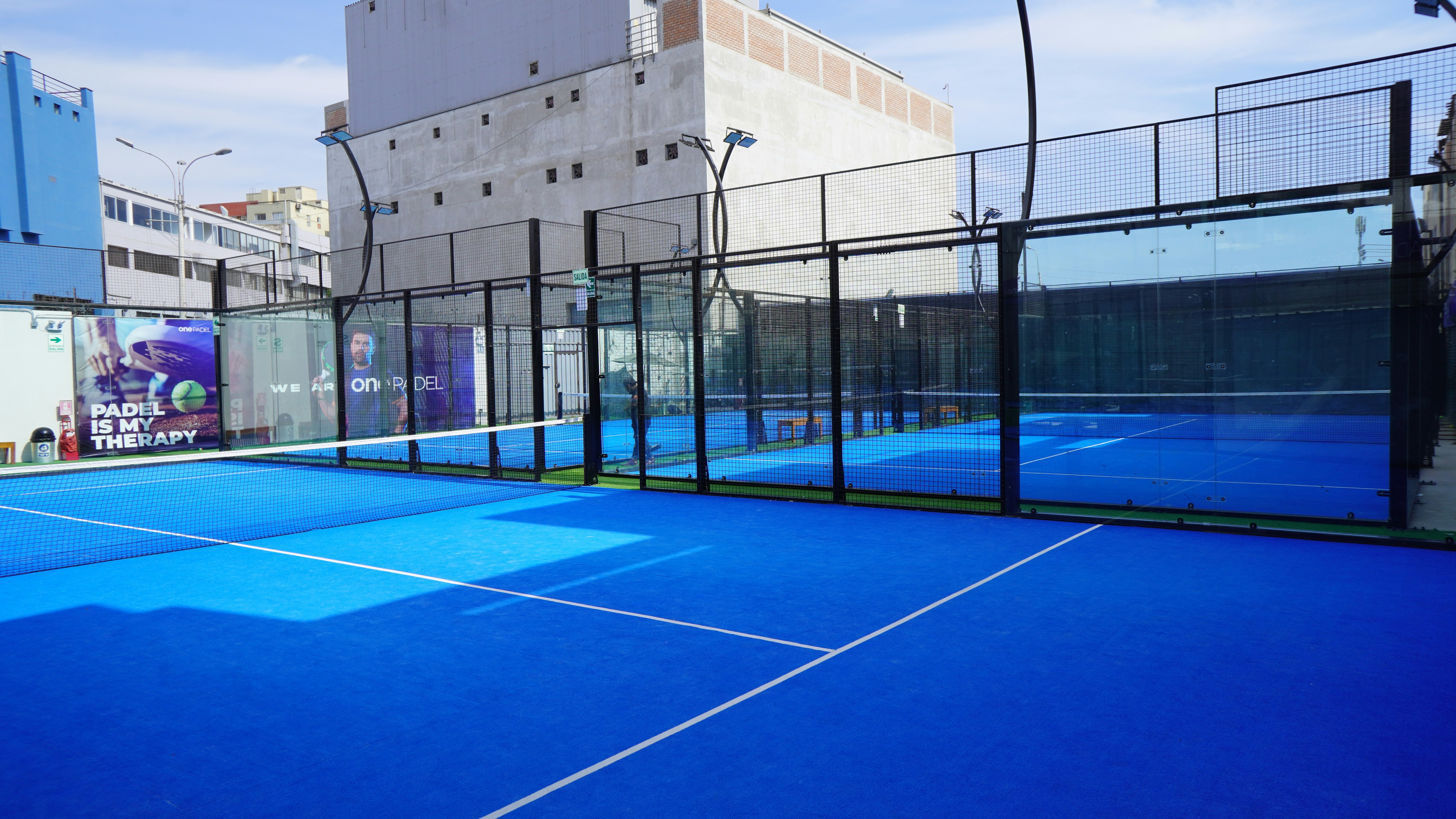 a tennis court with a blue tennis court and buildings in the background