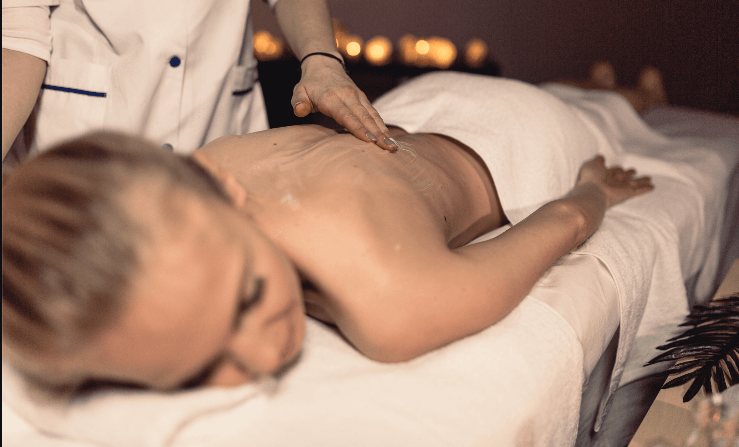 A woman receives a relaxing energy healing in a serene setting with soft lighting.