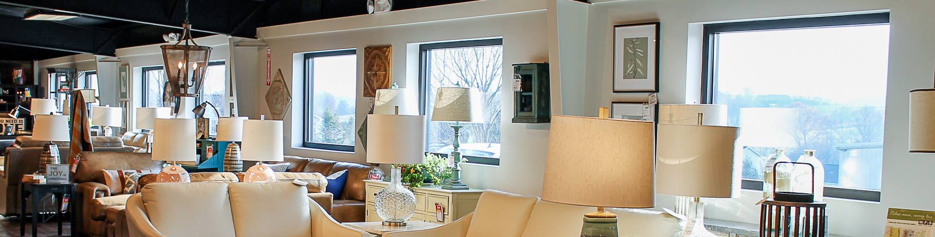 A bright showroom with large windows, filled with display furniture and home decor.