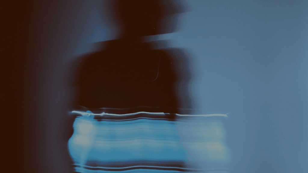 A blurred silhouette of a person against a dark background, with faint text displayed below.