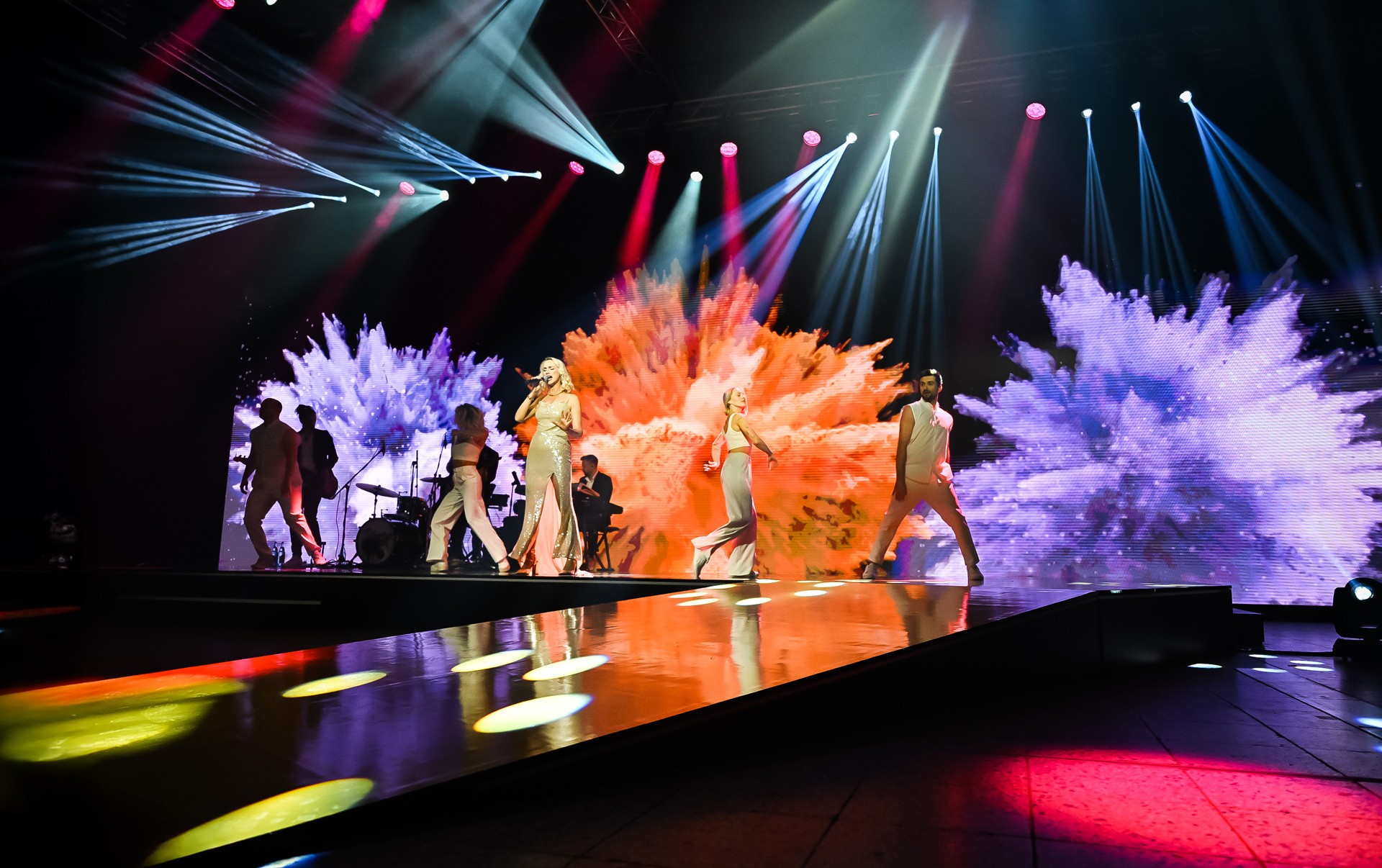 Sängerin und TänzerInnen auf felix Award Bühne mit Farbexplosionen auf der digitalen Screenfläche im Hintergrund