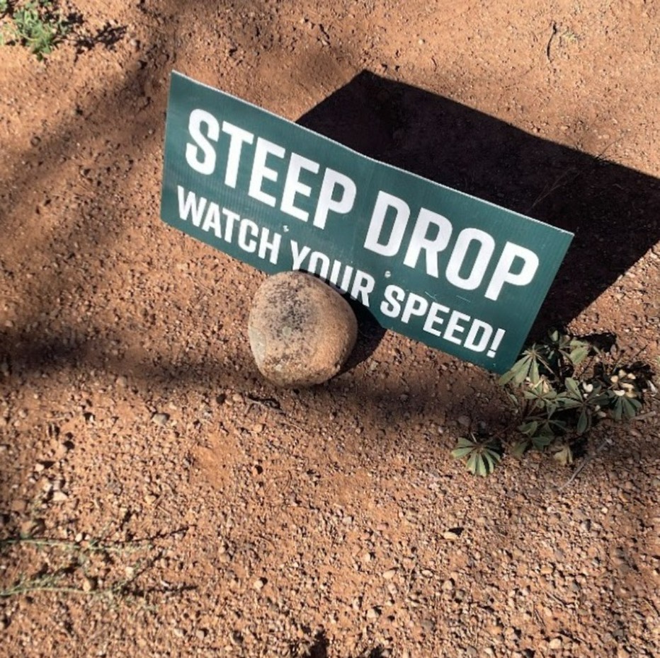A trail sign warns of a steep drop along the course.