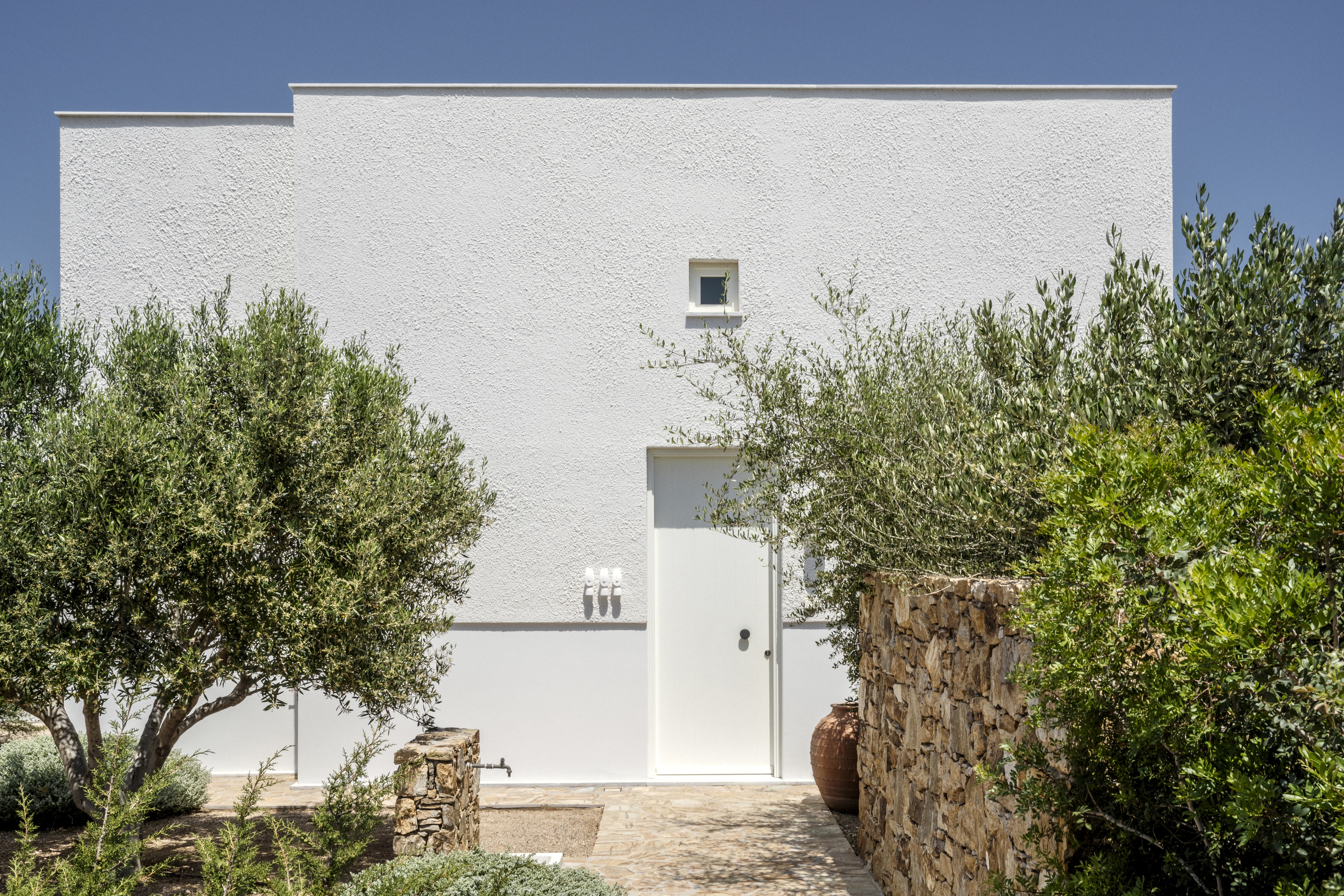 The entrance of a greek holiday home with trees outside