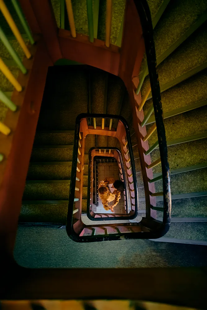 Brautpaar von oben fotografiert in einem spiralförmigen Treppenhaus, Fine Art Hochzeitsfotografie von Eva Sitko