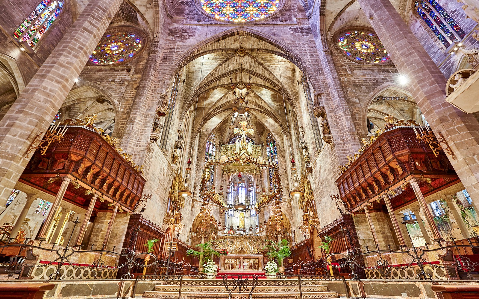 Interior de la Catedral de Palma con un altar ornamentado y vitrales.