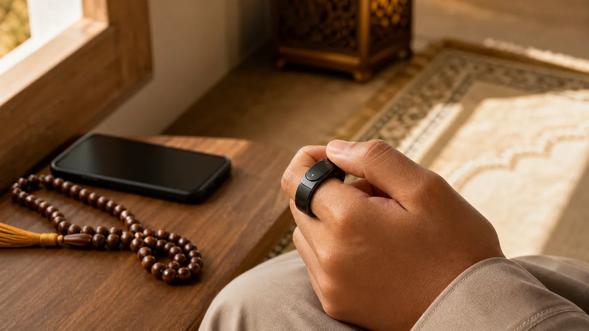 Smart tasbih ring used for quiet dhikr counting beside prayer beads and a face-down phone
