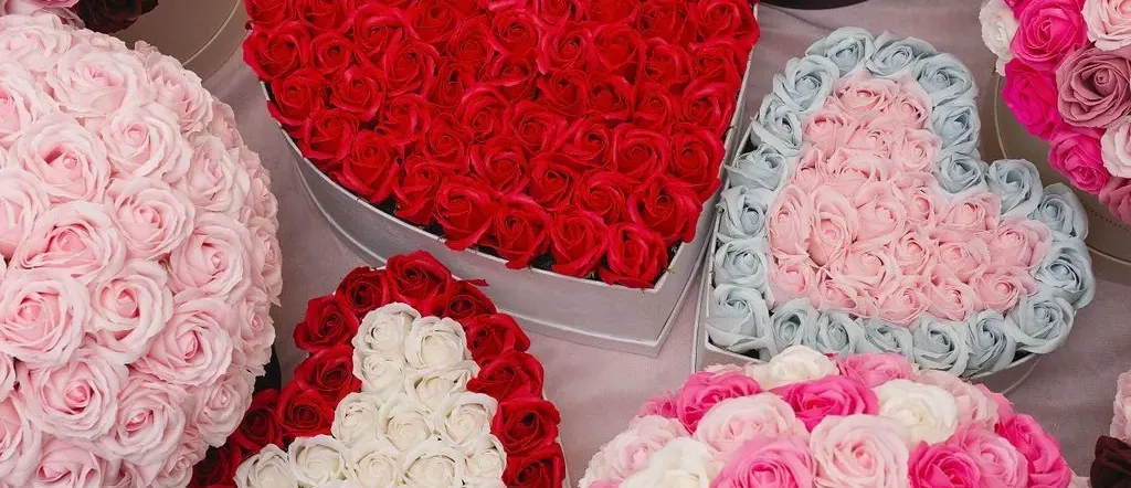 Heart-shaped and round arrangements of pink, red, and white soap roses in gift boxes