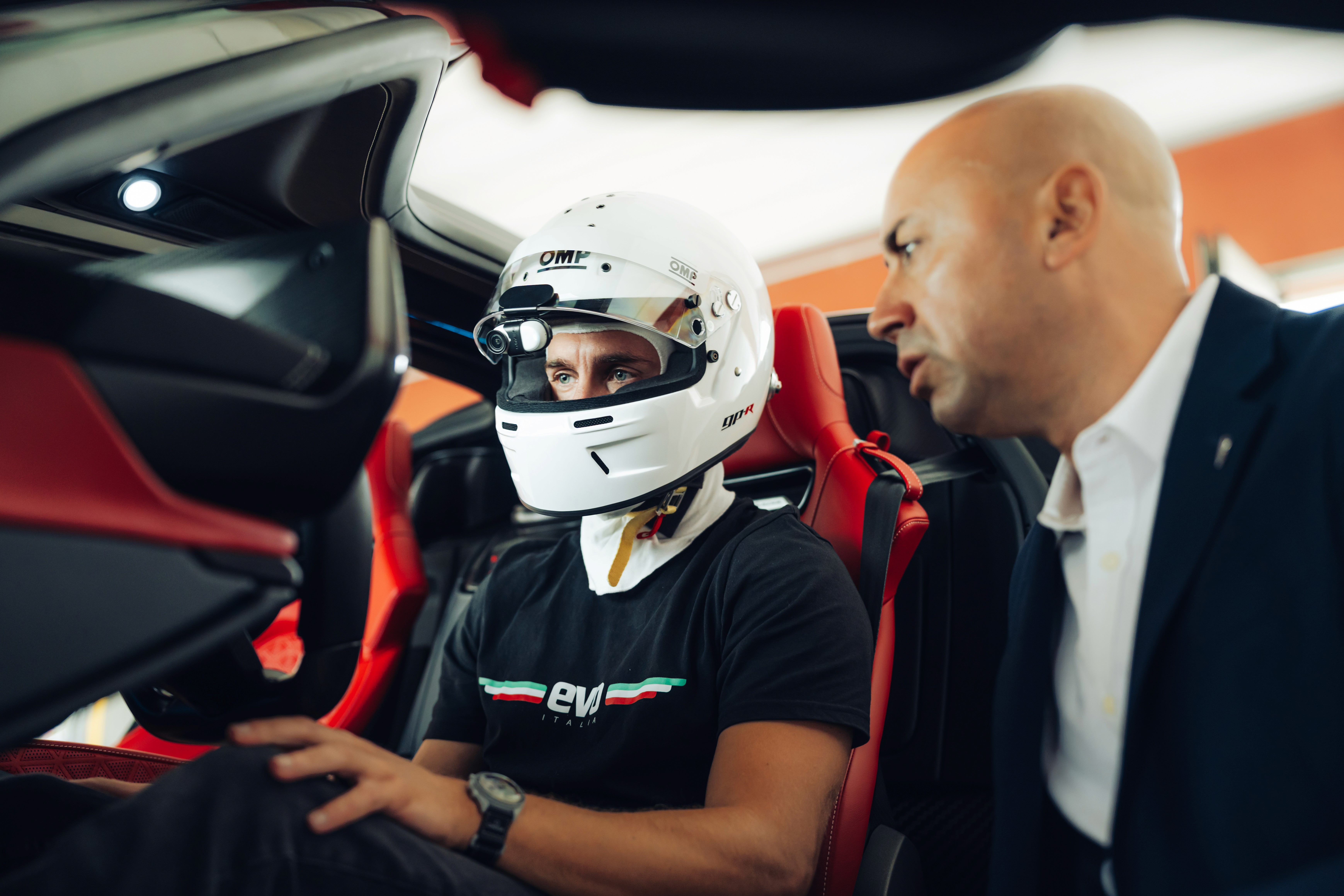 Pilota parla con persona vestita elegantemente a bordo di auto sportiva