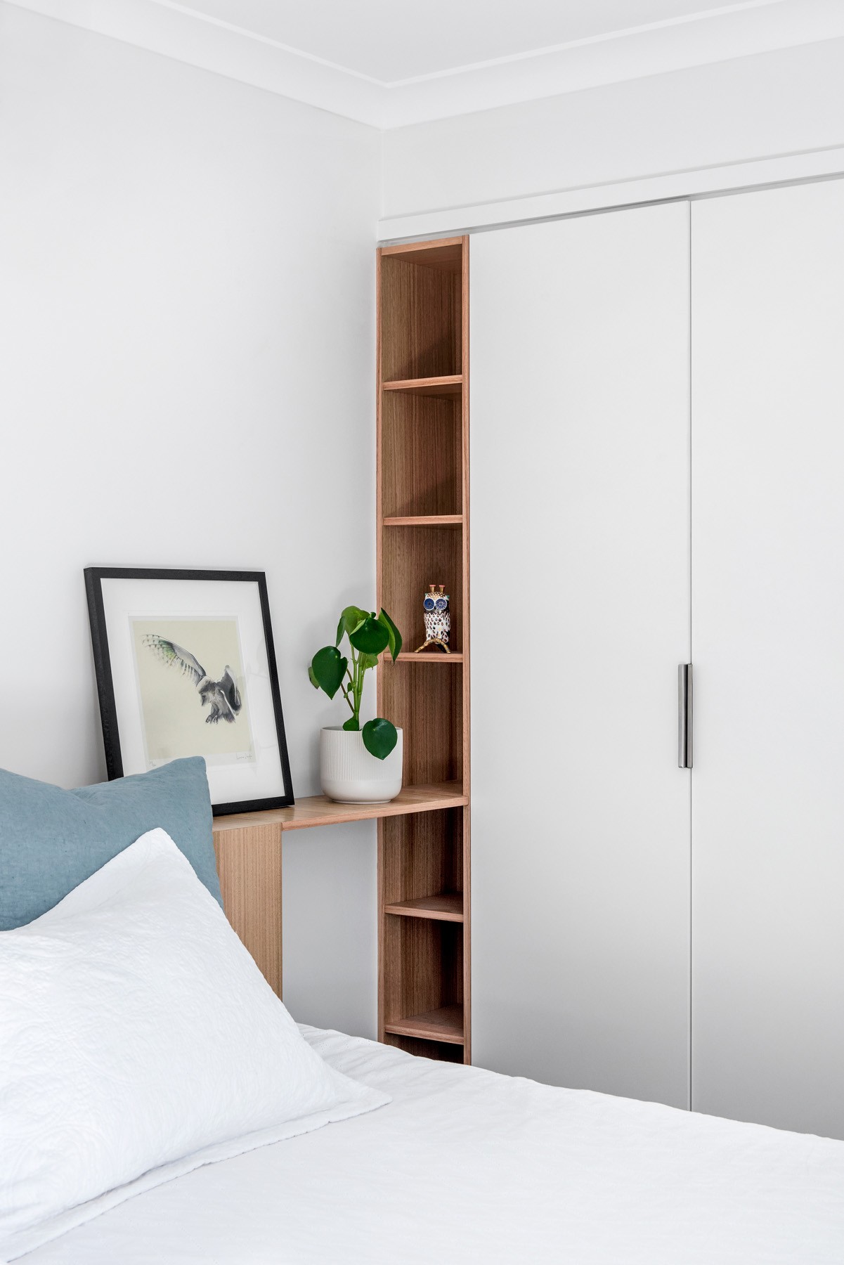 Bedroom storage detail at Oxford Cottage featuring integrated white joinery with open timber shelving softening the built-in cabinetry.