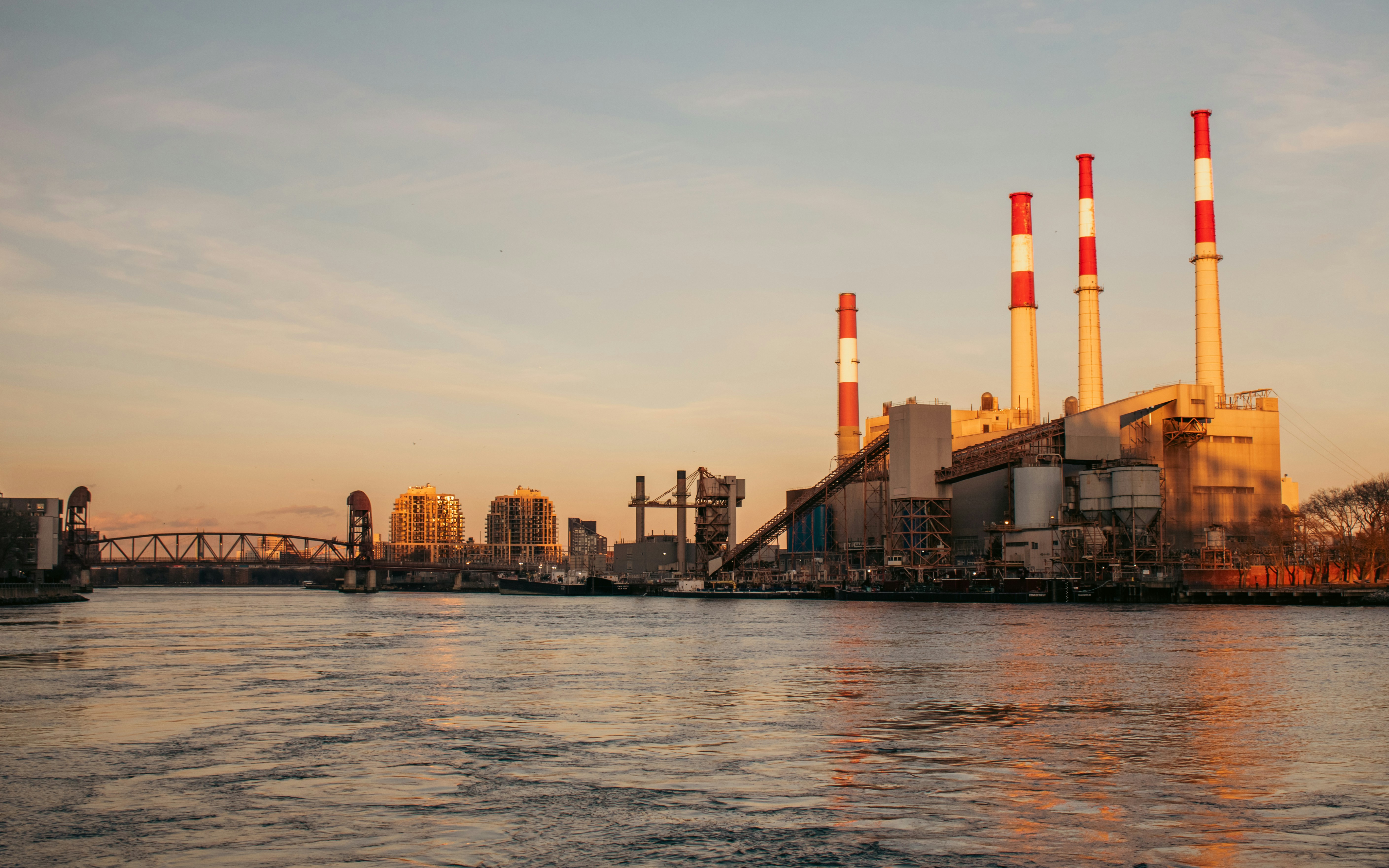 Power plant towers over a river at sunset.