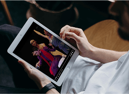 A decorative image featuring a person holding an iPad, displaying Opera and ballet content on the screen.