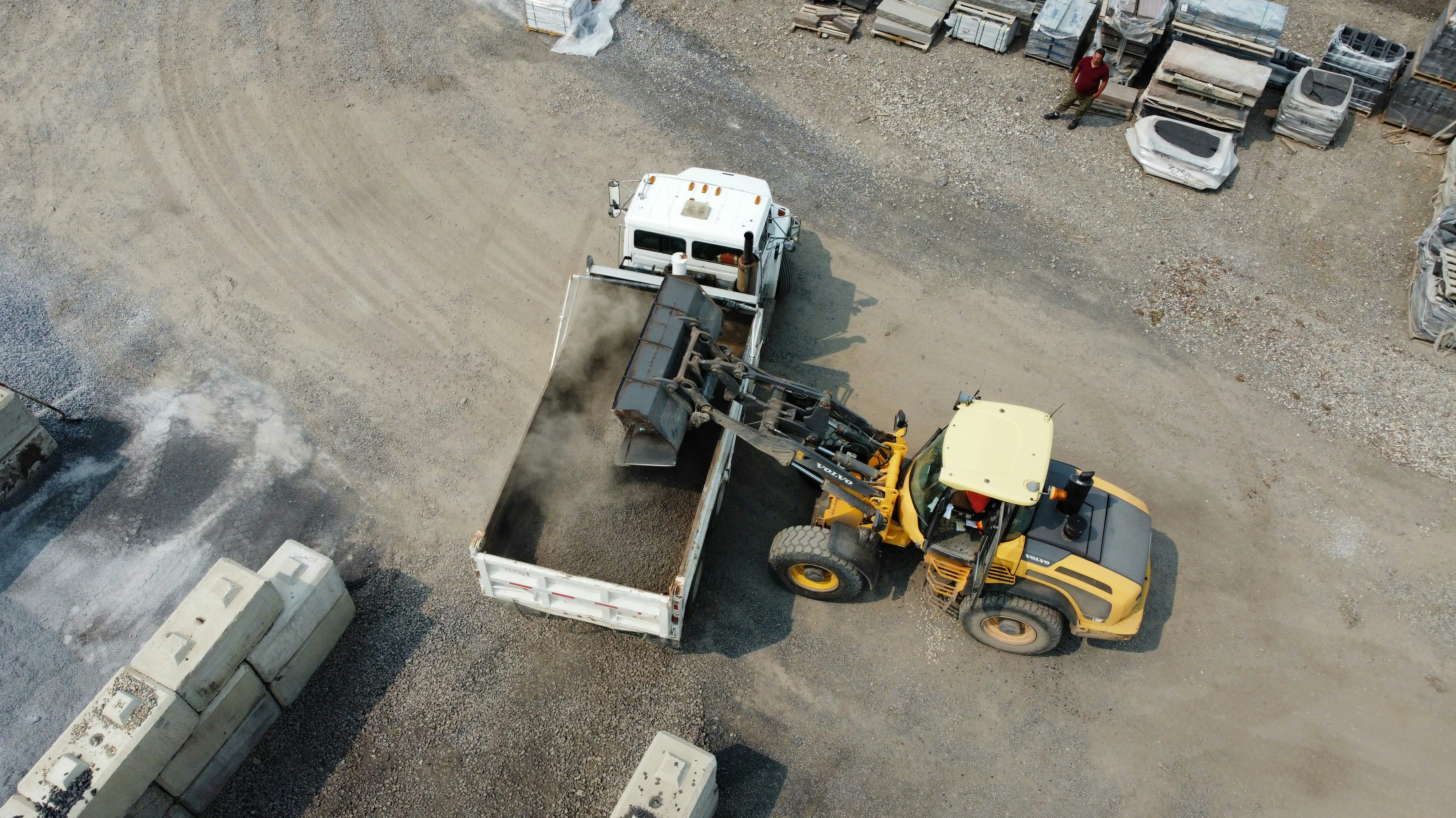 Loader dumping material into an open dump trailer at a job site