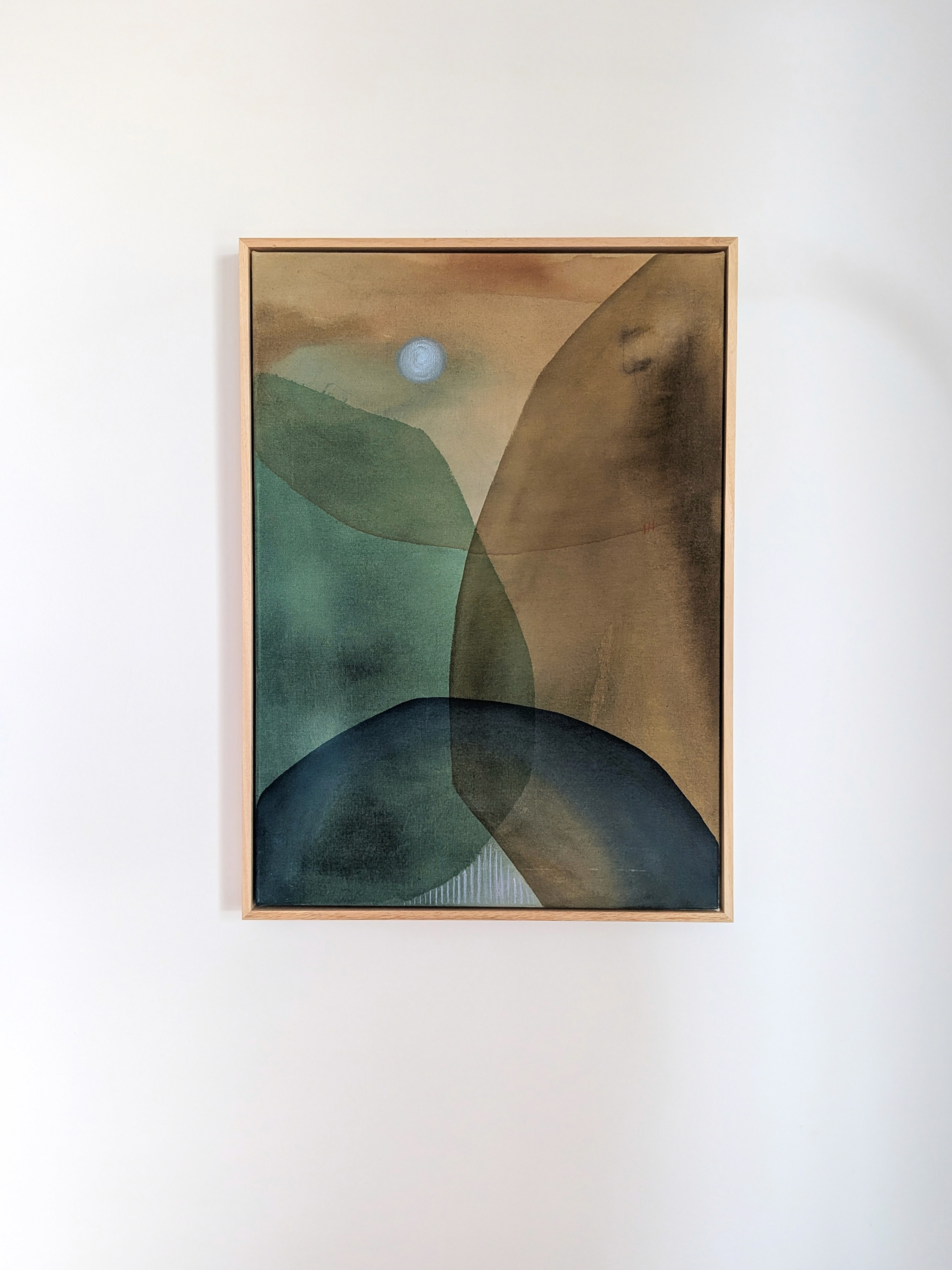 Abstract artwork featuring blue and beige shapes, displayed on a wall with a decorative plant nearby.