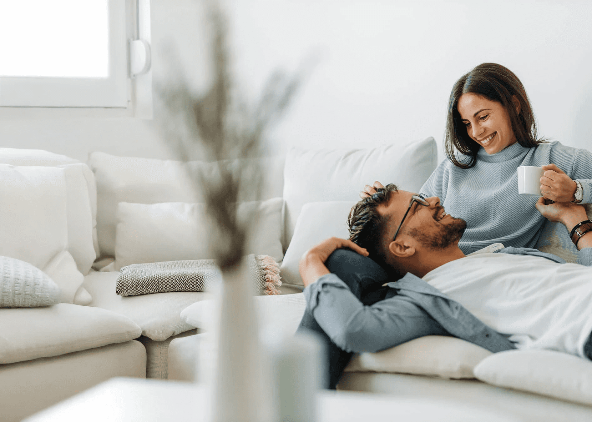 Woman smiling and her partner sitting on the couch representing Flouria’s fertility care