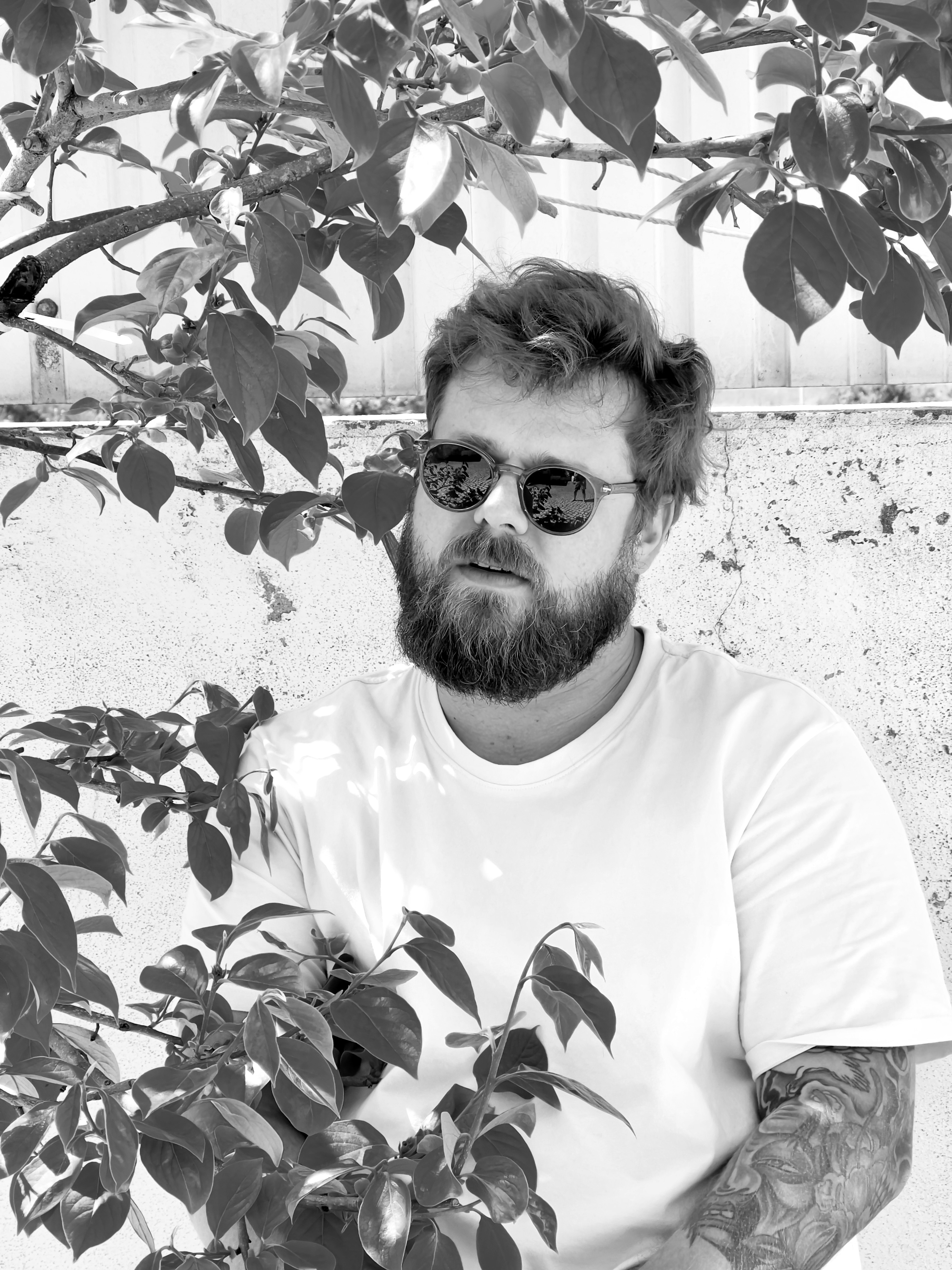 A thoughtful young person with dark hair gazes to the side, captured in soft black and white lighting.
