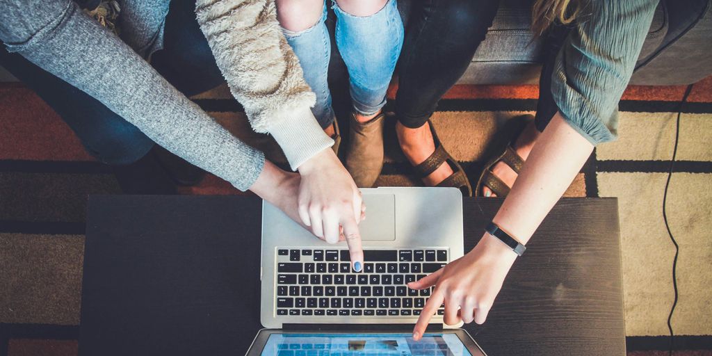 three person pointing the silver laptop computer