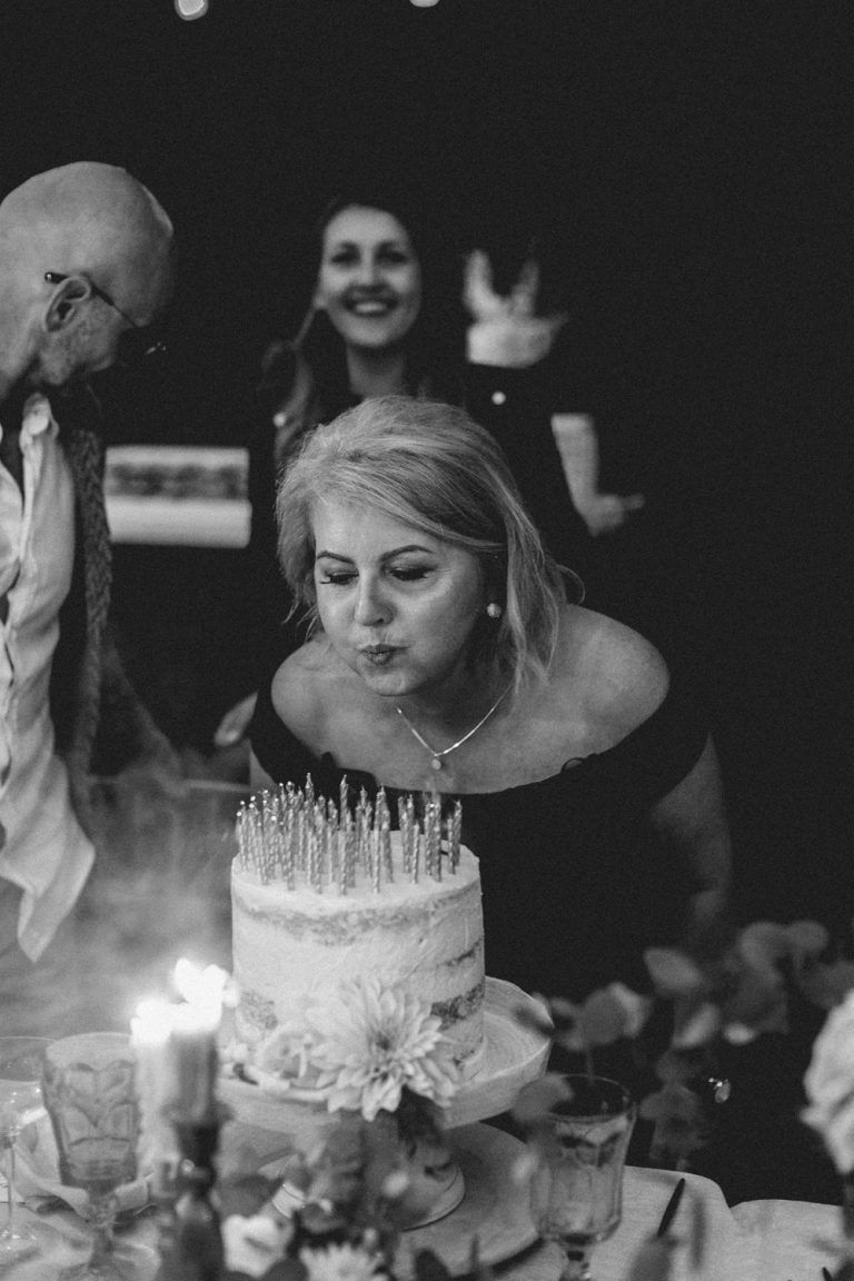 Black and white photo of a birthday celebration with a cake and guests