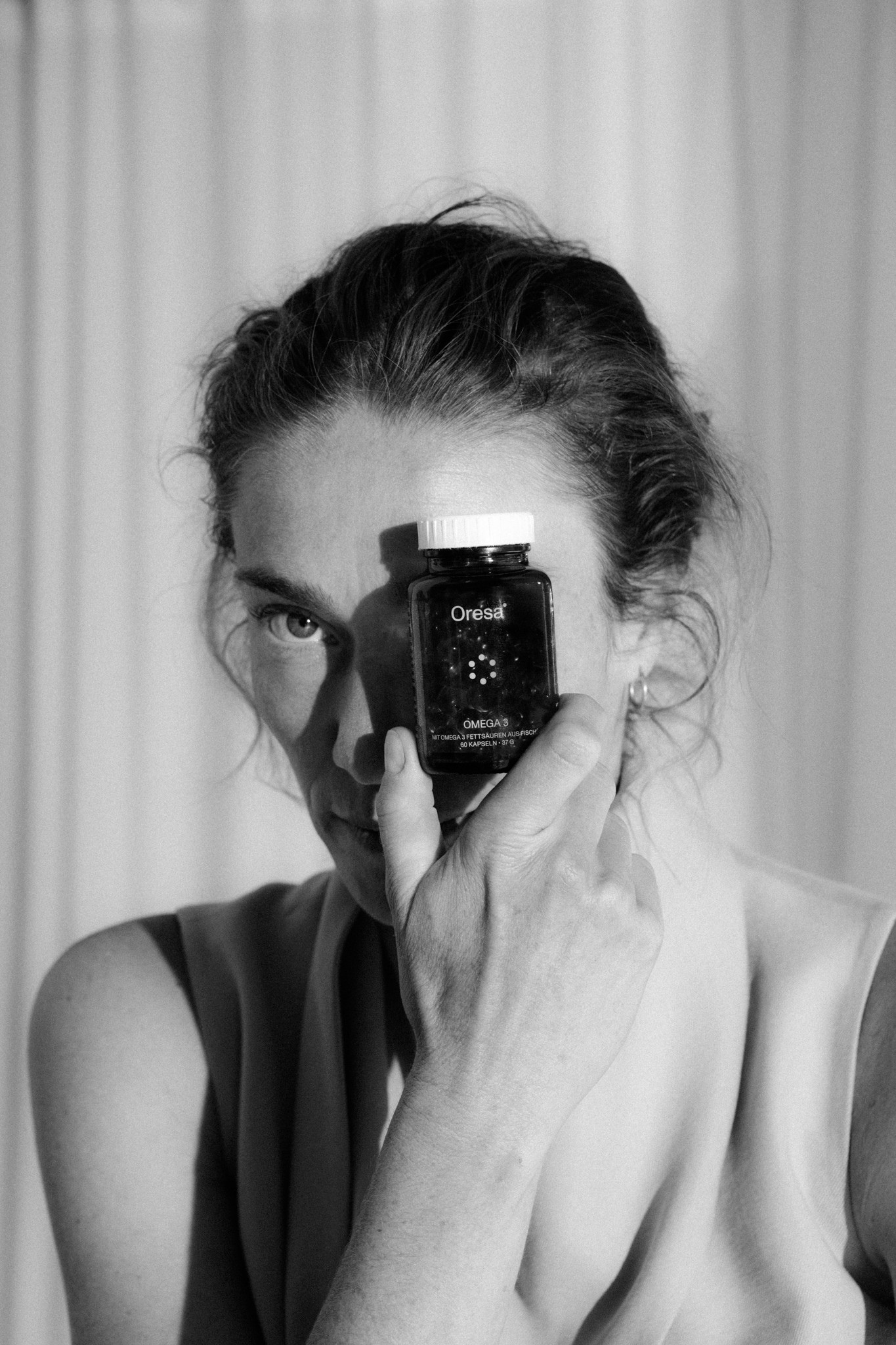 Frau hält Oresa Nahrungsergänzung vor dem Gesicht – natürliche Mikronährstoffe ohne Zusatzstoffe