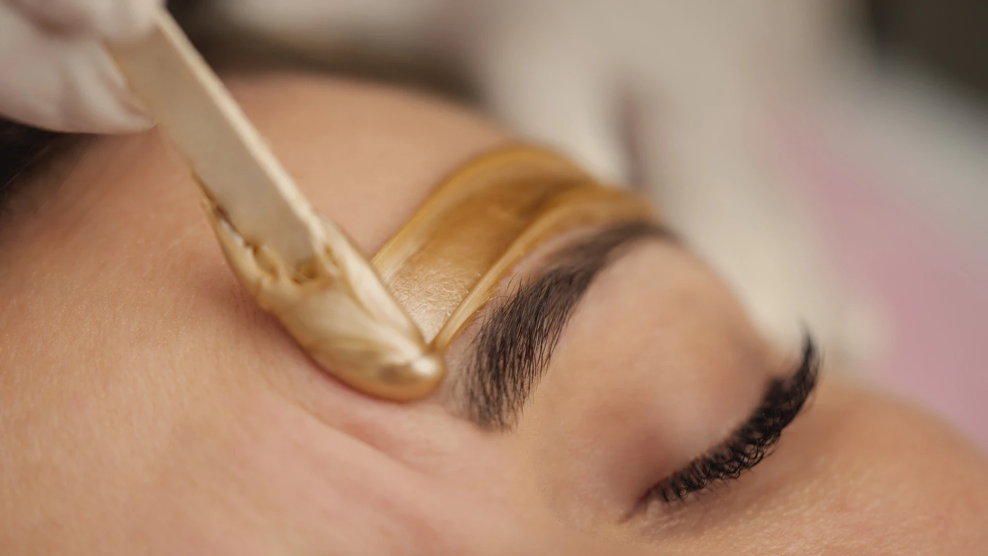 a technician working on waxing a guest's eye brow