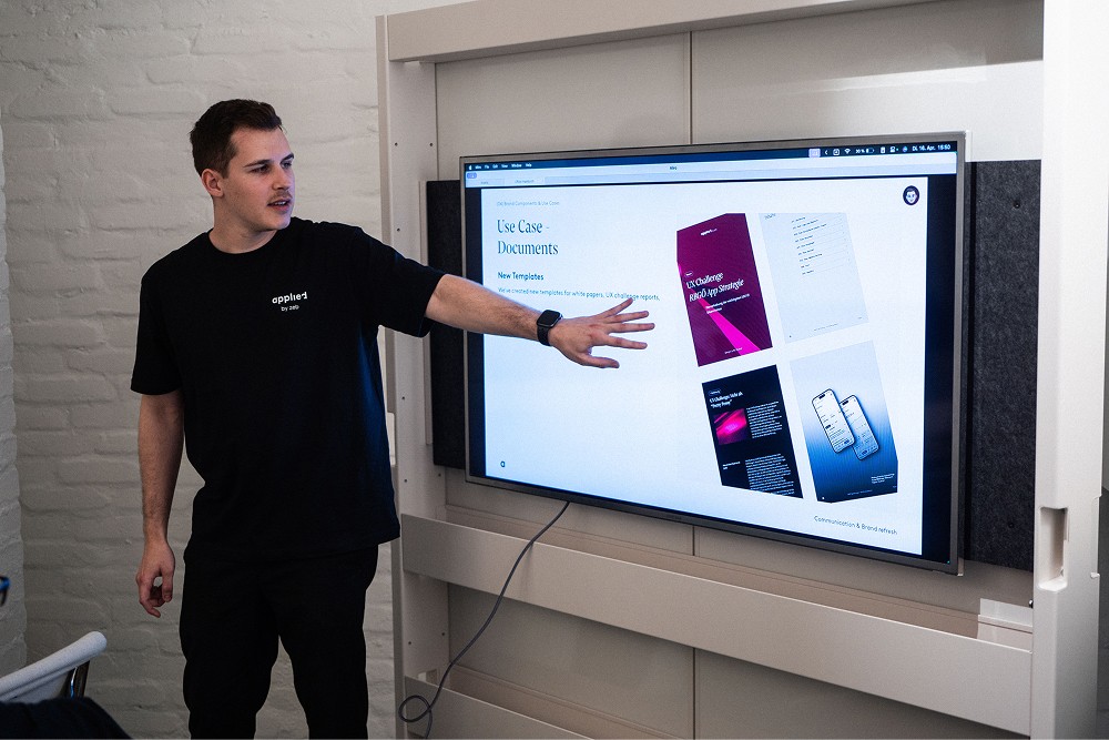 Mitarbeiter präsentiert Designinhalte an einem großen Bildschirm.