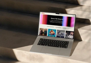Homepage design for Netflix's global WannaTalkAboutIt.com, shown on a laptop outdoors.