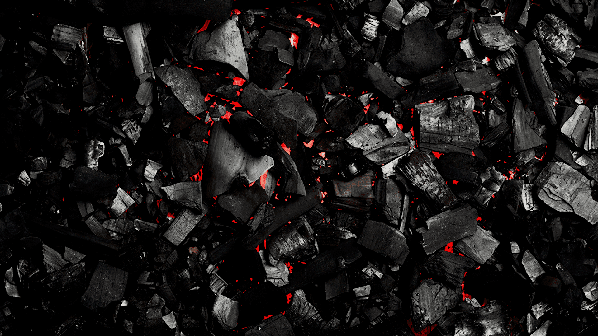 Glowing red embers scattered across dark charcoal, suggesting resilience and renewal.