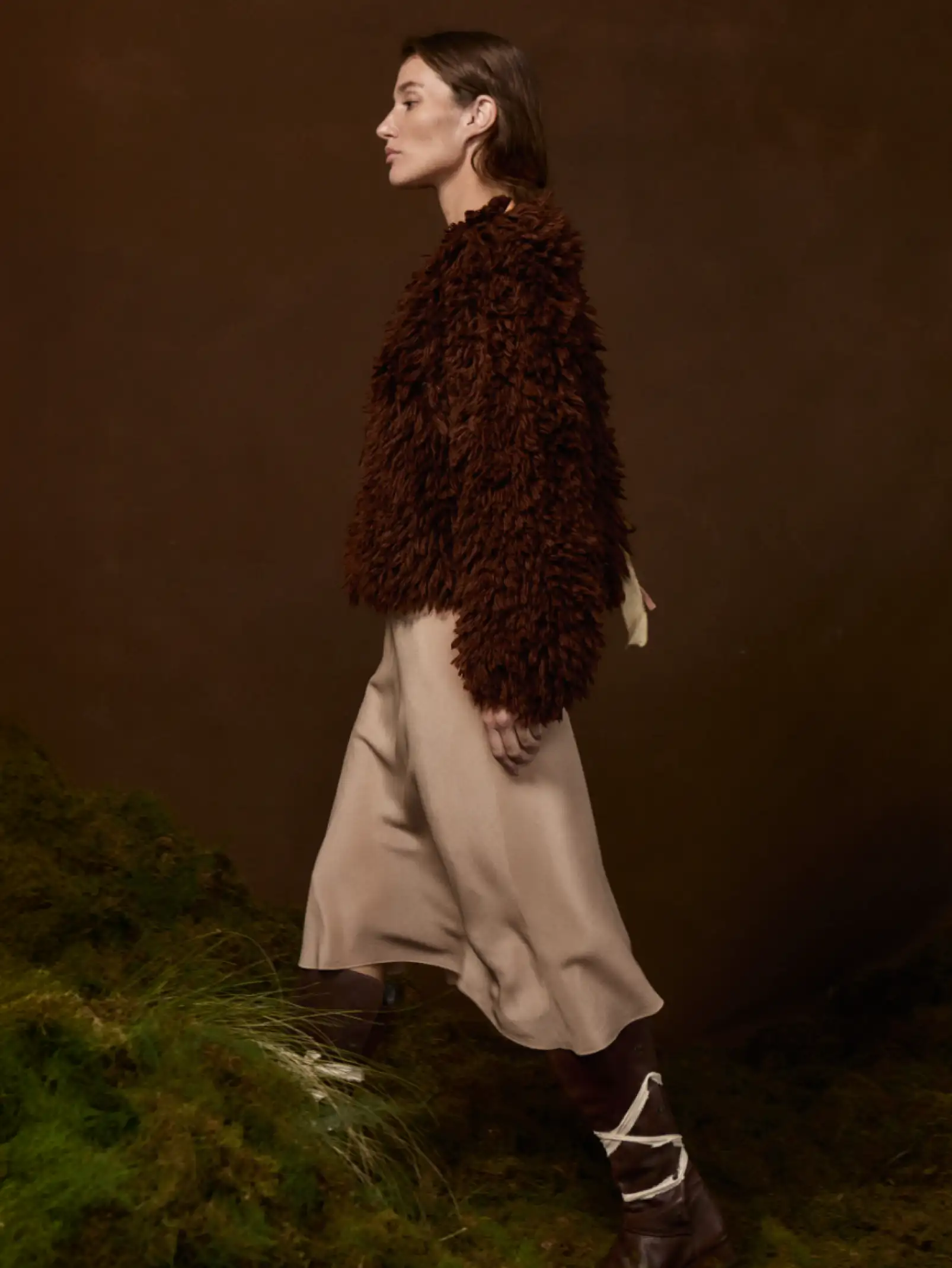 Modelo con abrigo marrón y falda beige sobre fondo terroso para colección otoño inspirada en la naturaleza.
