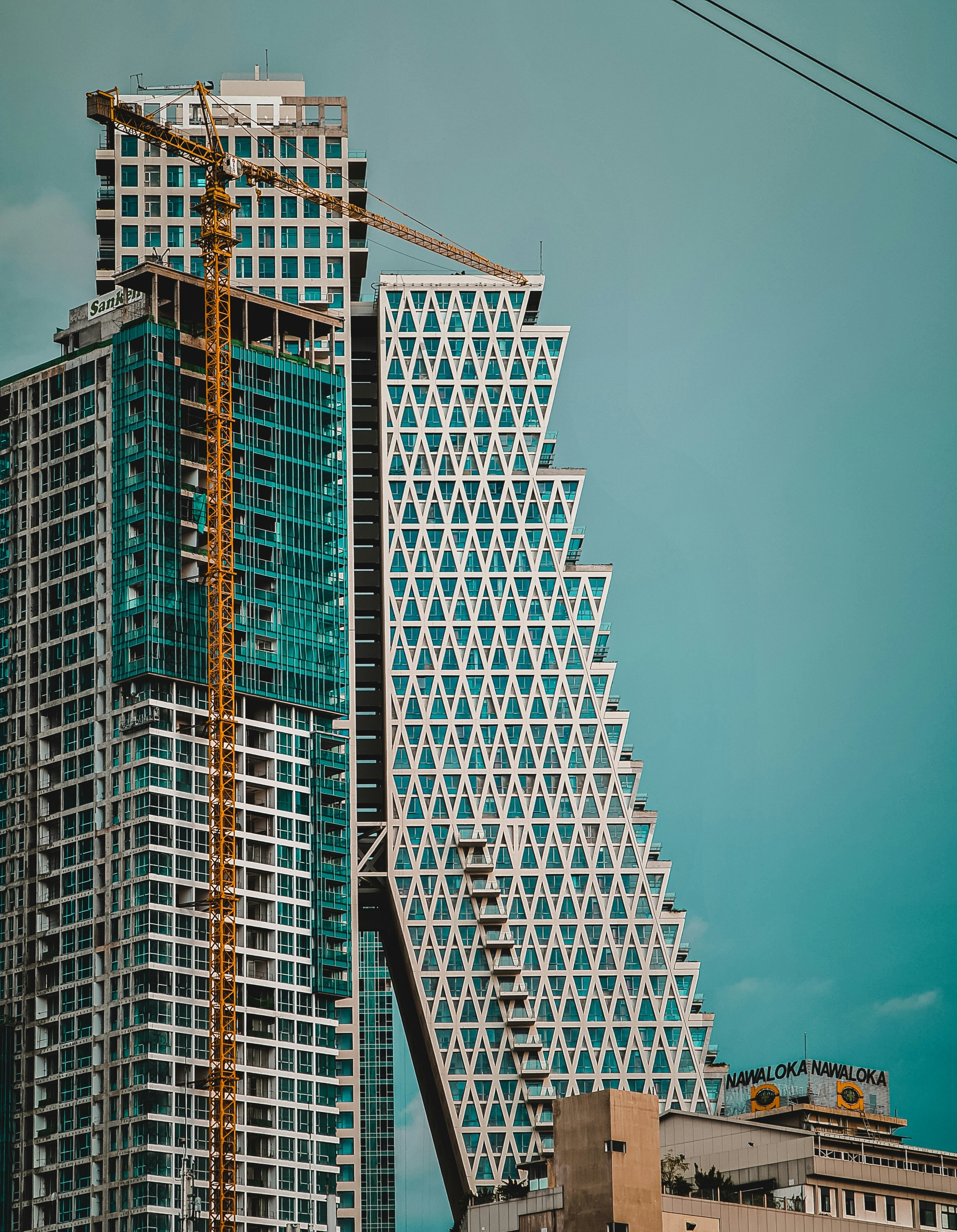 Smiling young man with short hair poses against a dark background, wearing a green button-up shirt.