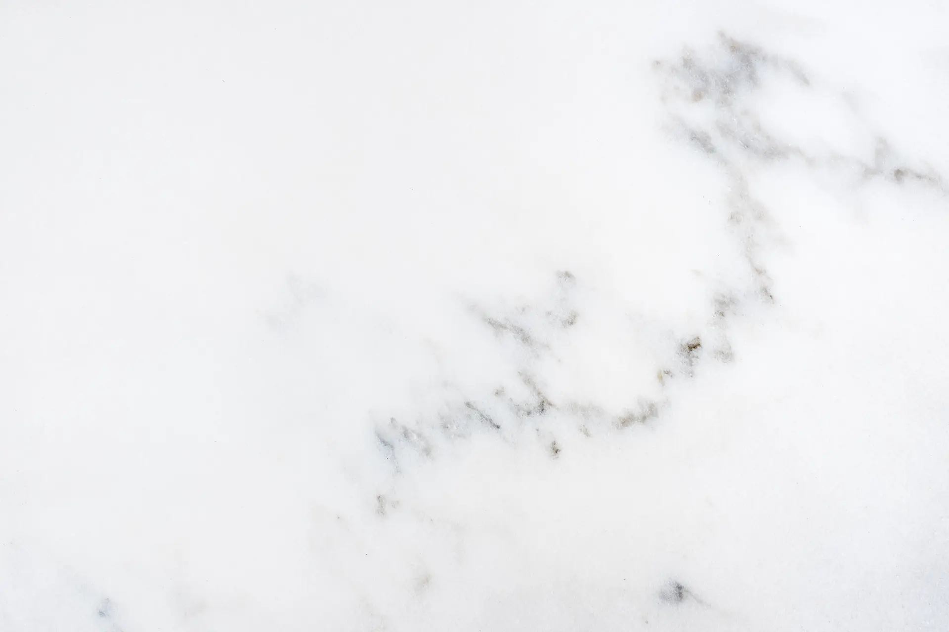 A slab of classic Italian Carrara marble, showcasing its white background and soft, feathery gray veining.