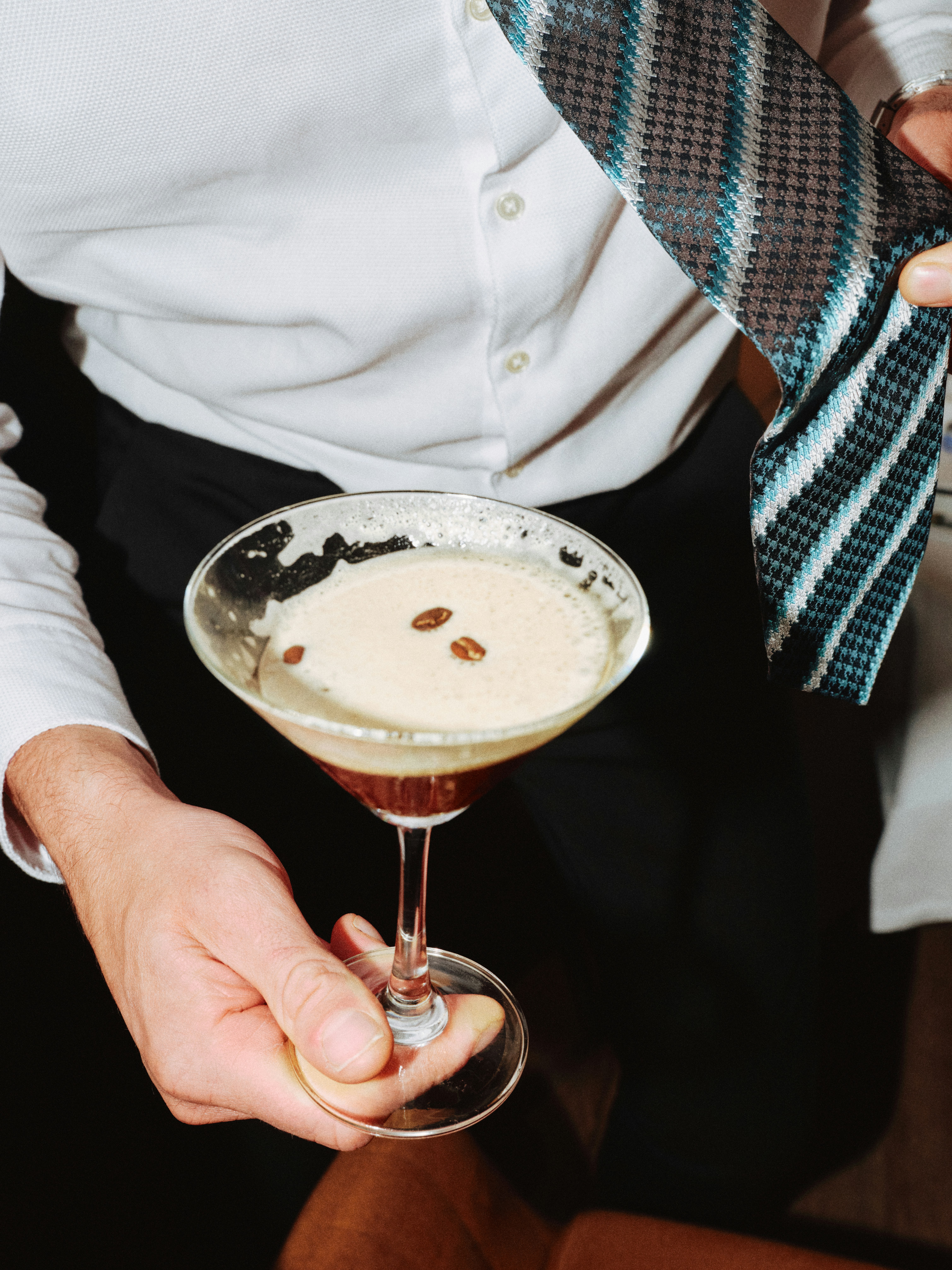 man holding a martini with coffee beans