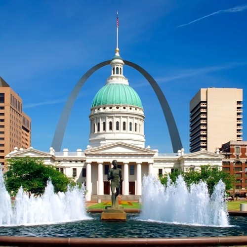 Old Courthouse with a green dome, fountains in front, and St. Louis Gateway Arch in the background, under a clear blue sky.