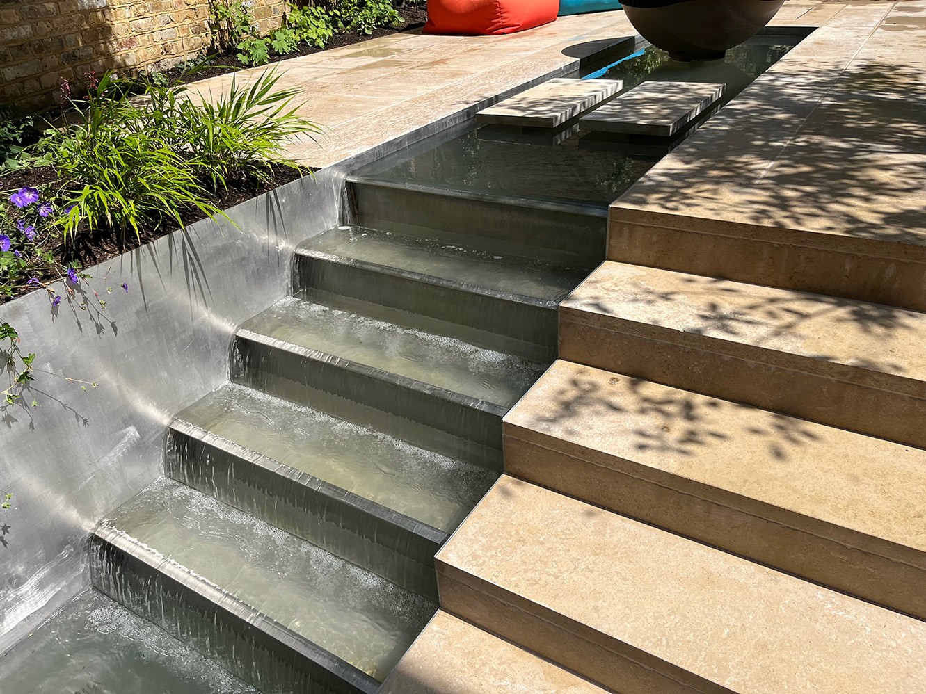 Close-up of stone steps with layered design, surrounded by greenery and sunlight casting shadows.