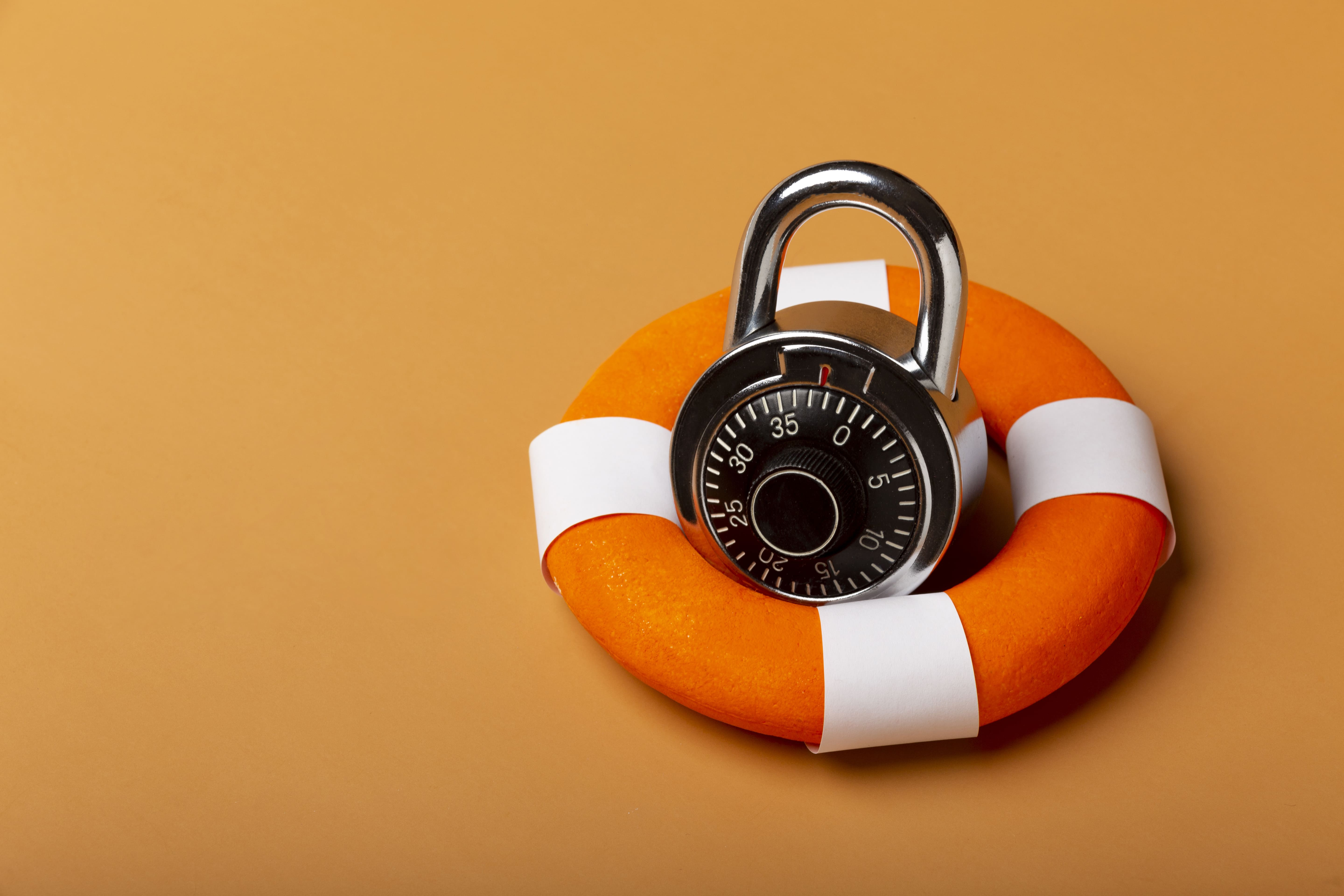 A smiling young man with crossed arms, wearing a plaid shirt and white t-shirt, poses against a dark background.