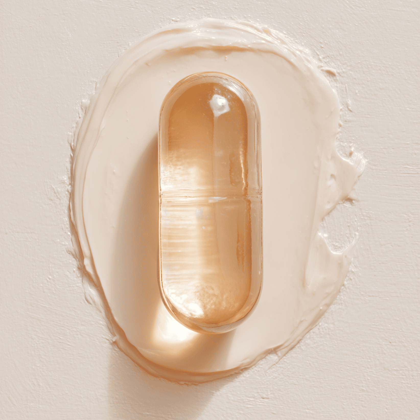 Translucent capsule resting within a smooth layer of balm, showing a clean, controlled formulation on a neutral surface.