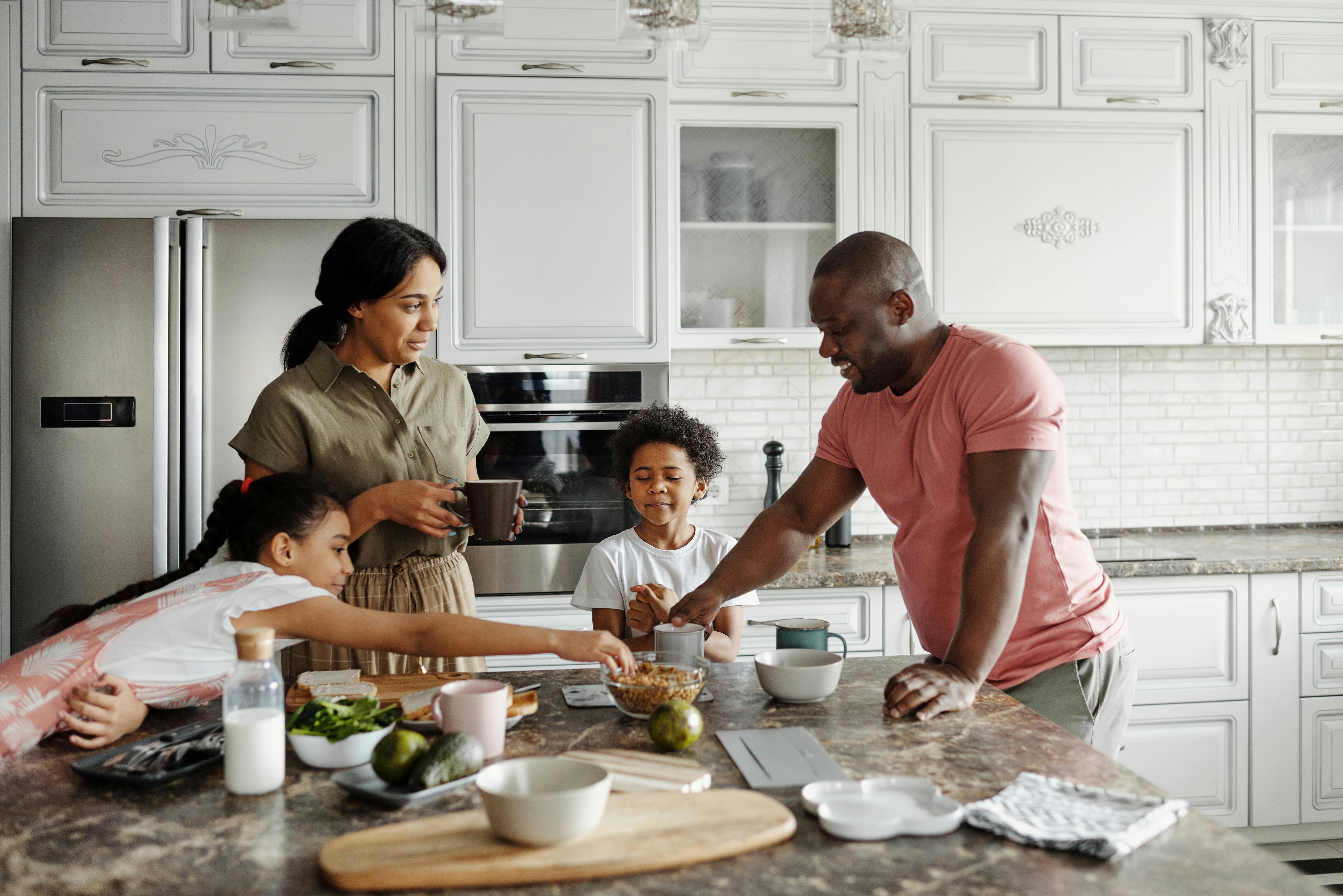 A family, including two young children, is cooking in their bright kitchen.